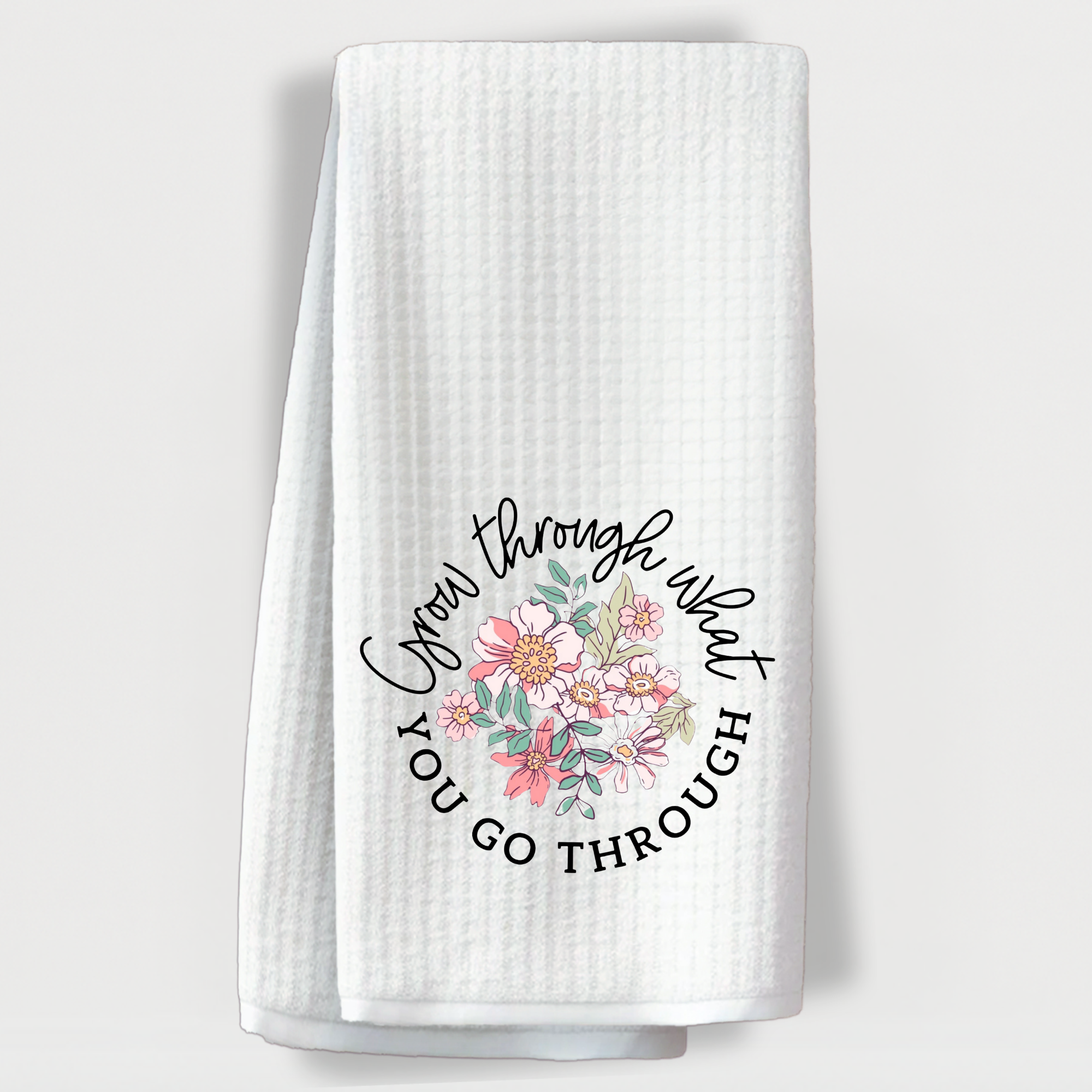 "Motivational towel with floral wreath and quote 'Grow through what you go through' in script font."
