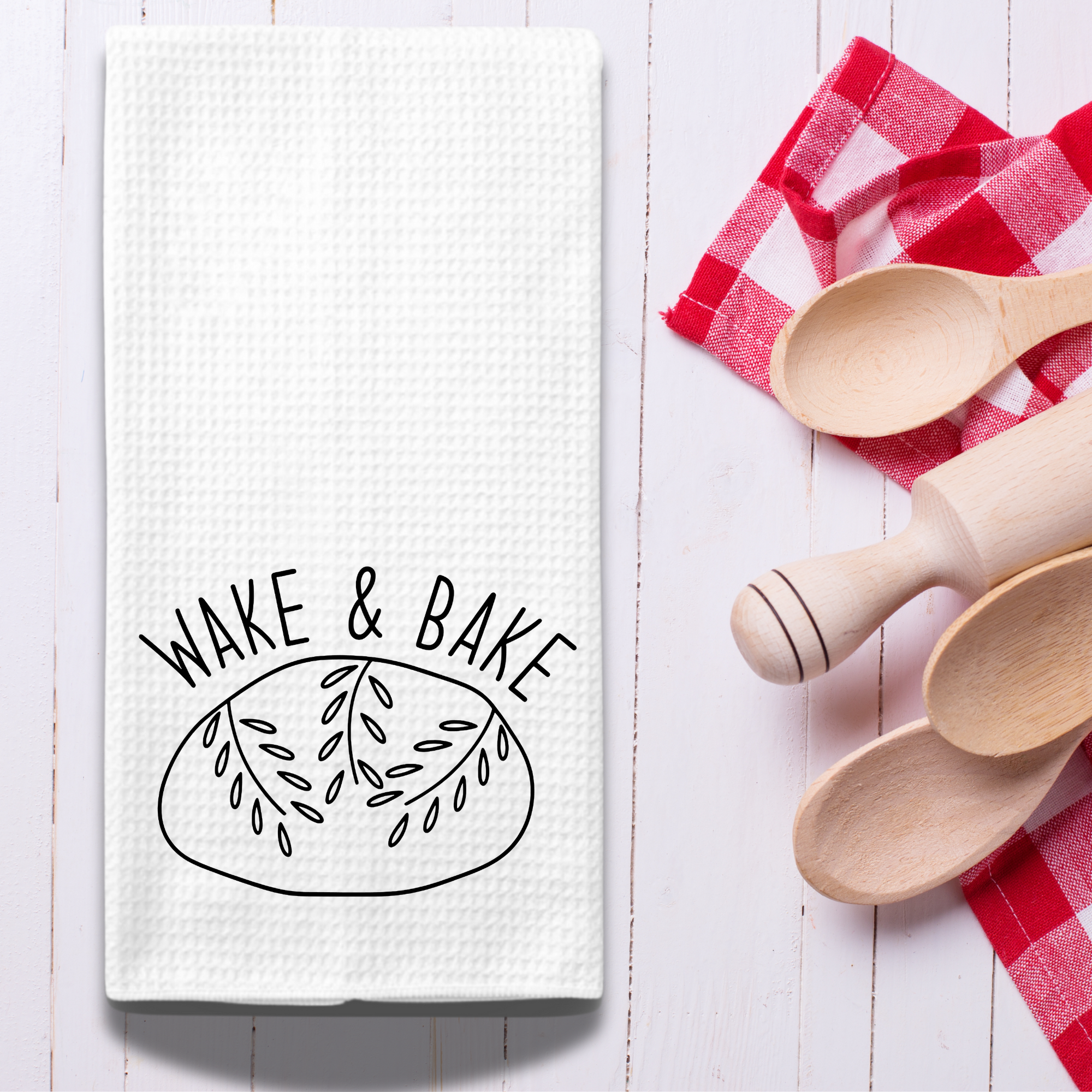 Kitchen towel with sourdough loaf design styled with rolling pin, wooden spoons, and red check cloth.