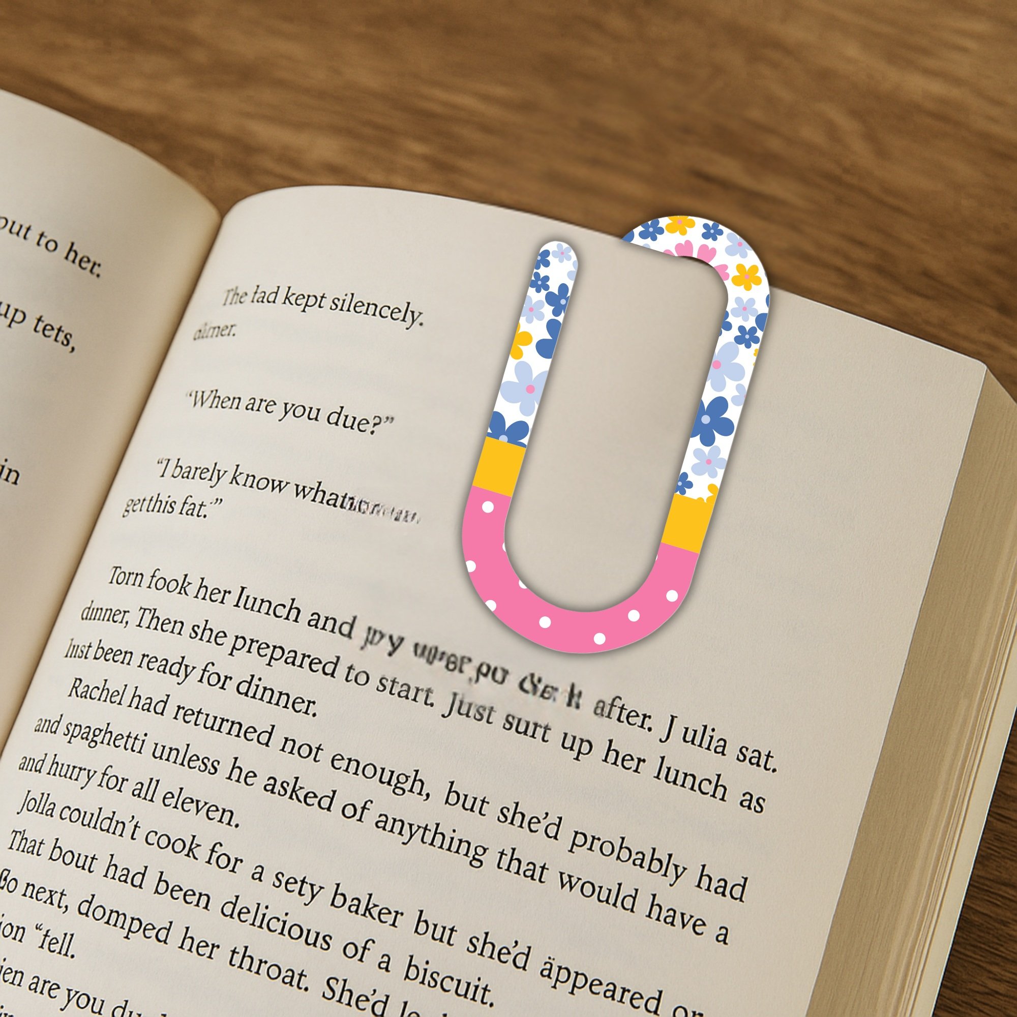 Floral oversized paper clip used as a bookmark inside an open novel.