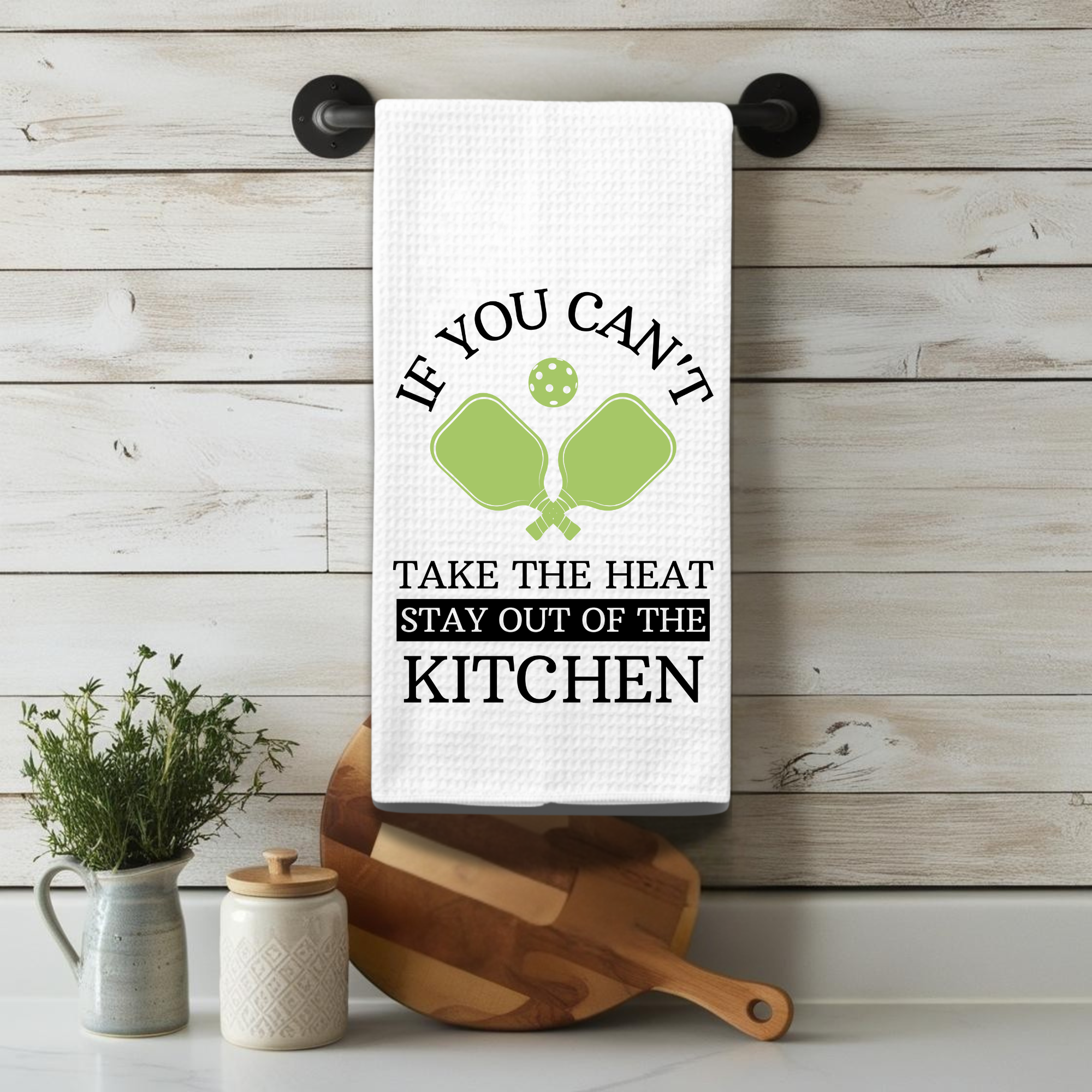 Funny pickleball quote towel hanging on a rustic farmhouse bar above kitchen utensils and herbs.