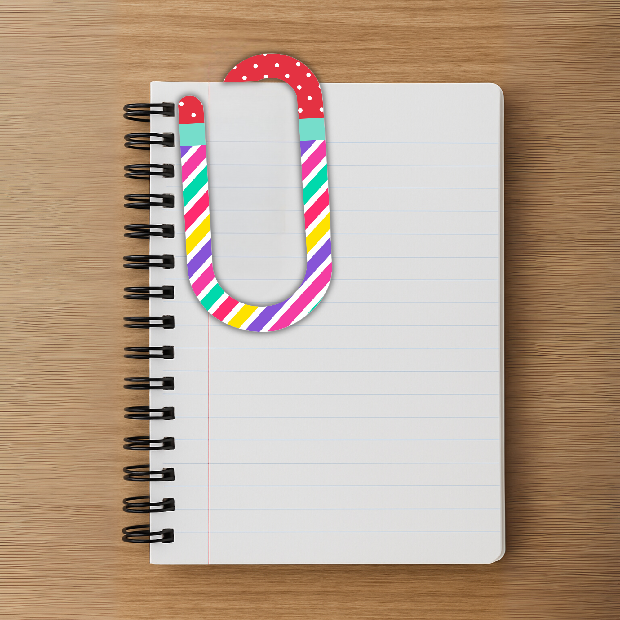 Large red and teal polka dot paperclip clipped onto spiral notebook.