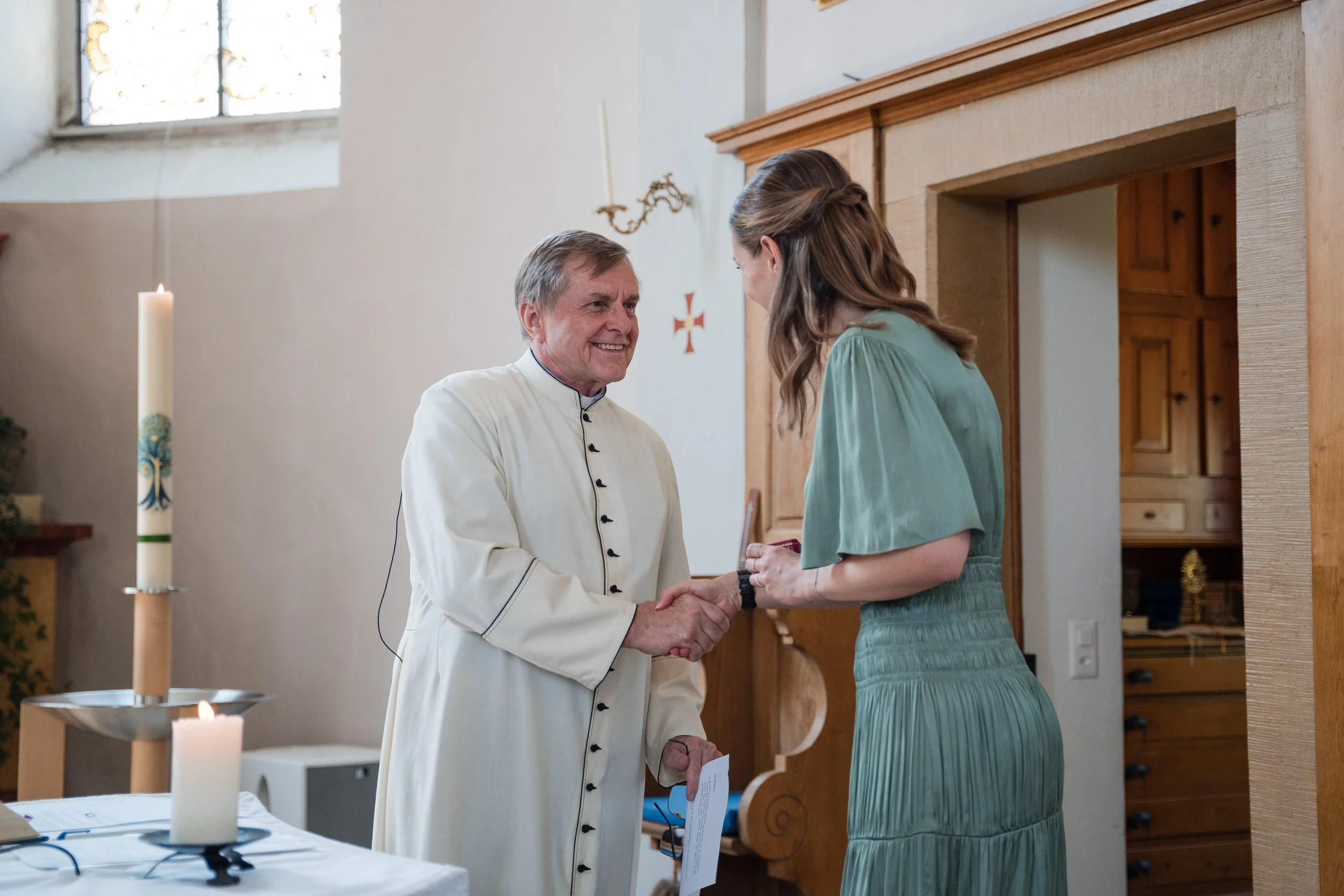Ein Priester spricht mit einer jungen Frau während einer religiösen Zeremonie in einer Kirche.