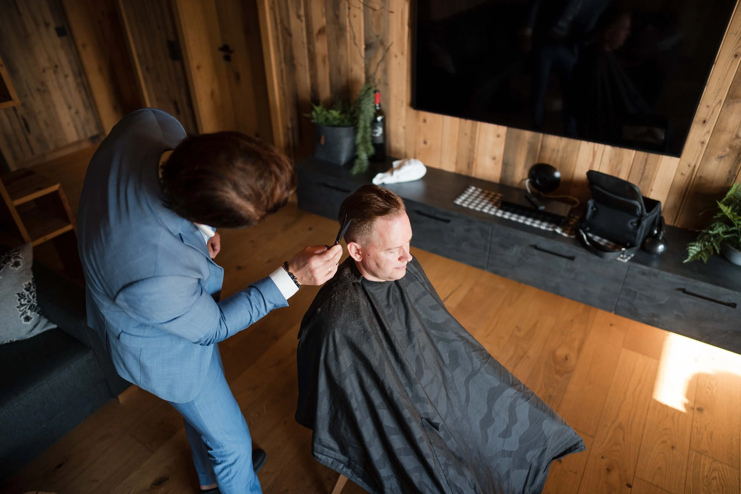 Mann bekommt einen Haarschnitt in einem modernen, holzvertäfelten Raum von einem Friseur.