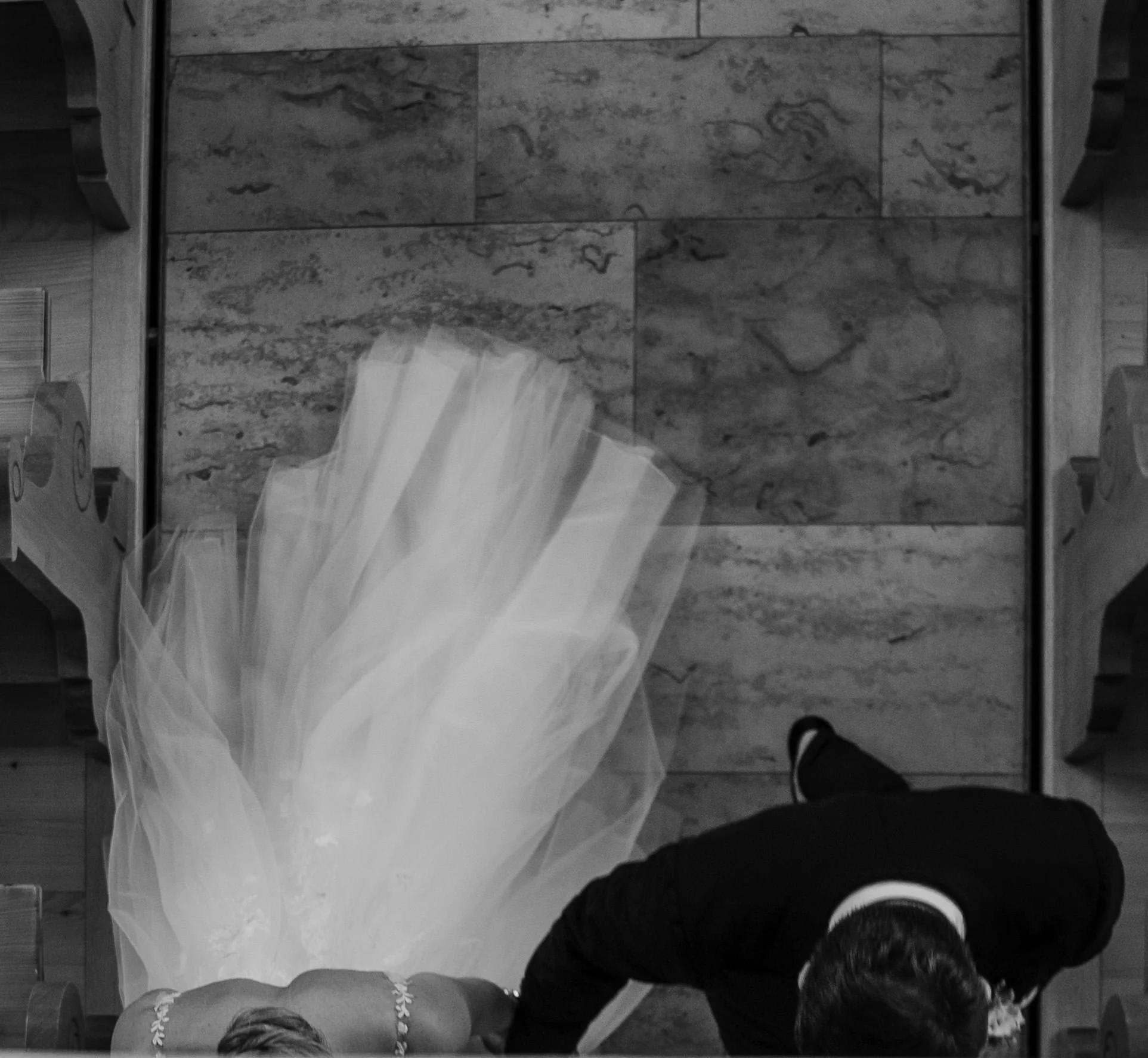 Blick von oben auf eine Braut in einem weißen Kleid und einen Bräutigam in einem schwarzen Anzug bei einer Hochzeit.