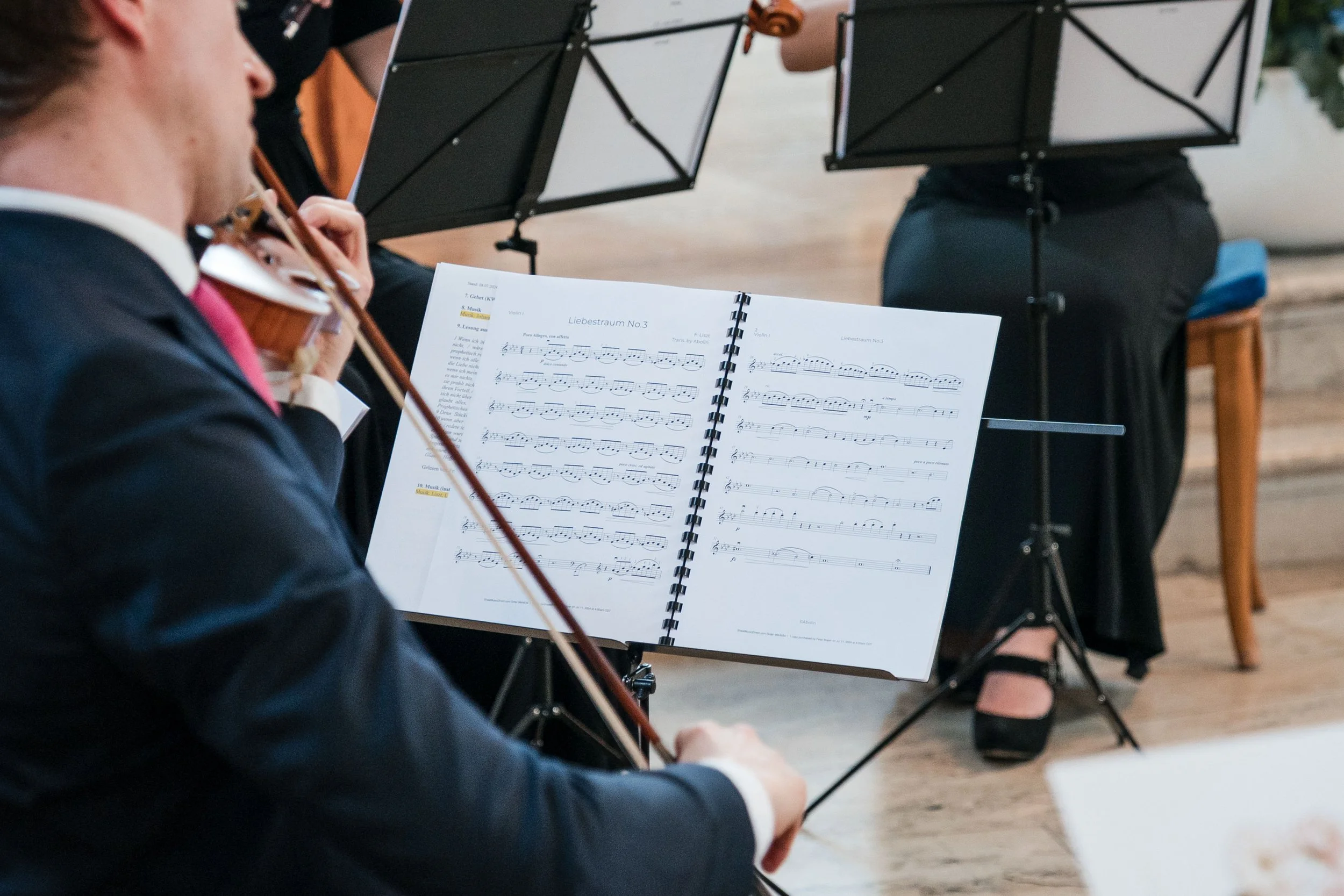 Ein Orchester spielt, mit einigen Musikern, die Notenblätter auf Notenständern lesen.
