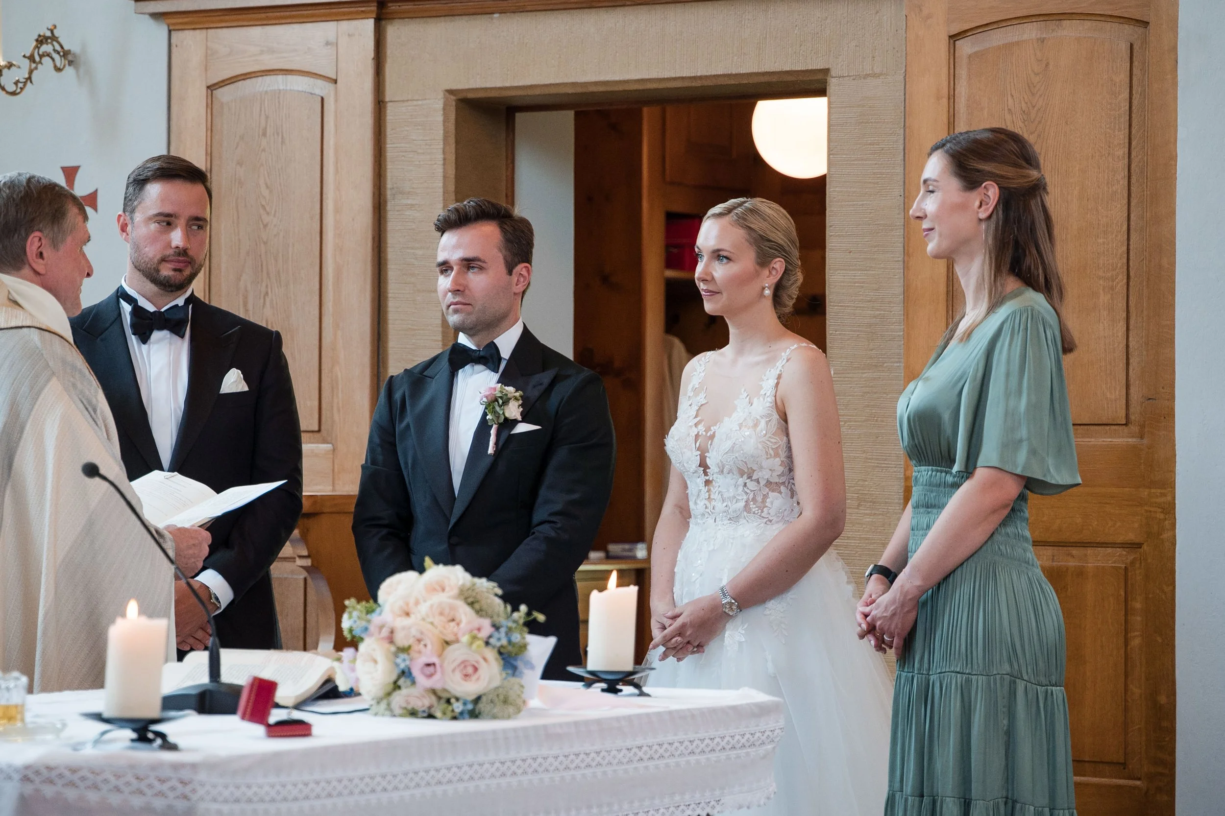 Hochzeitsszene mit Braut, Bräutigam, Trauzeugen, Pfarrer und Brautmoden in einer Kirche
