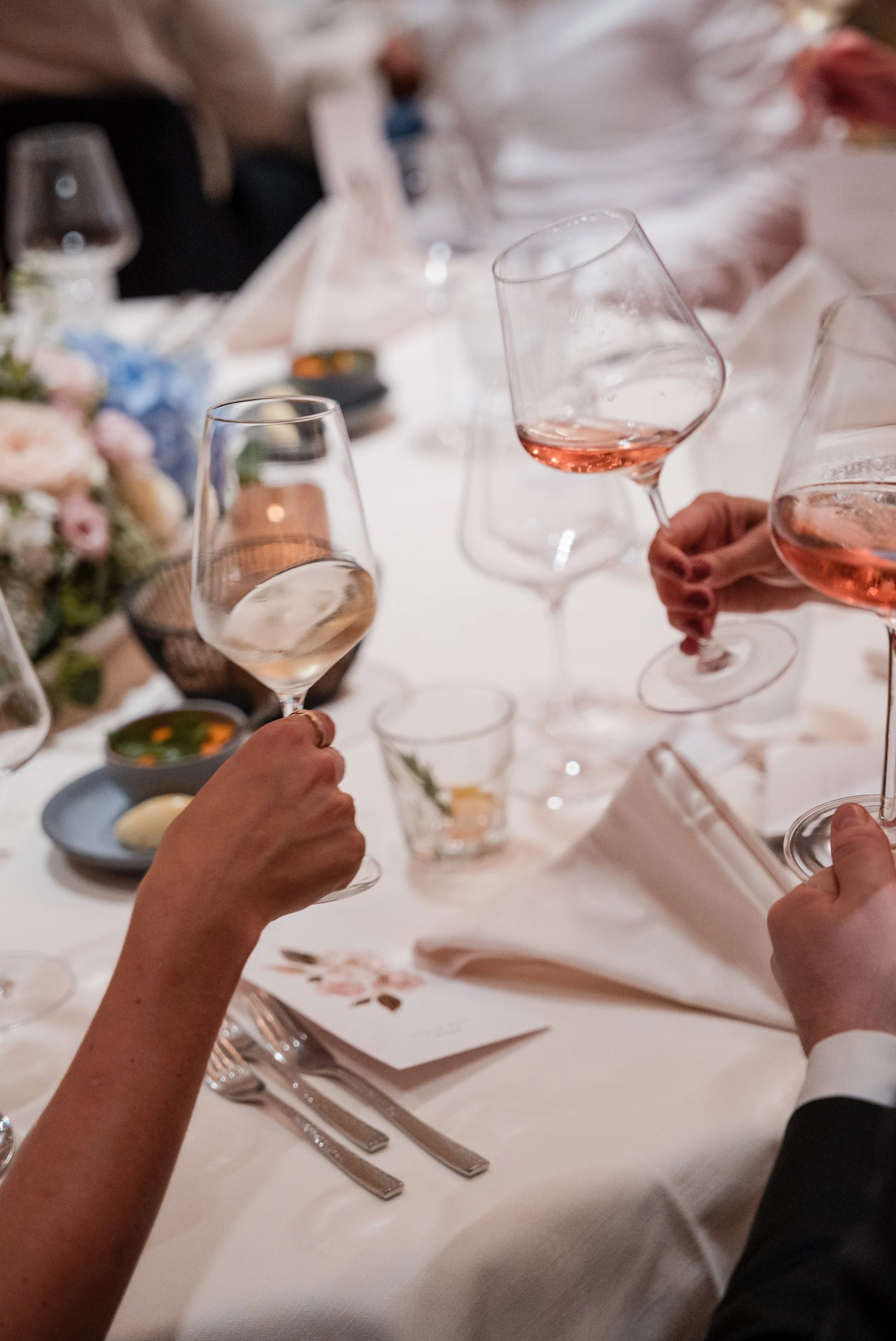 Menschen prosten sich mit Weingläsern mit rosé Wein bei einer festlichen Mahlzeit an.