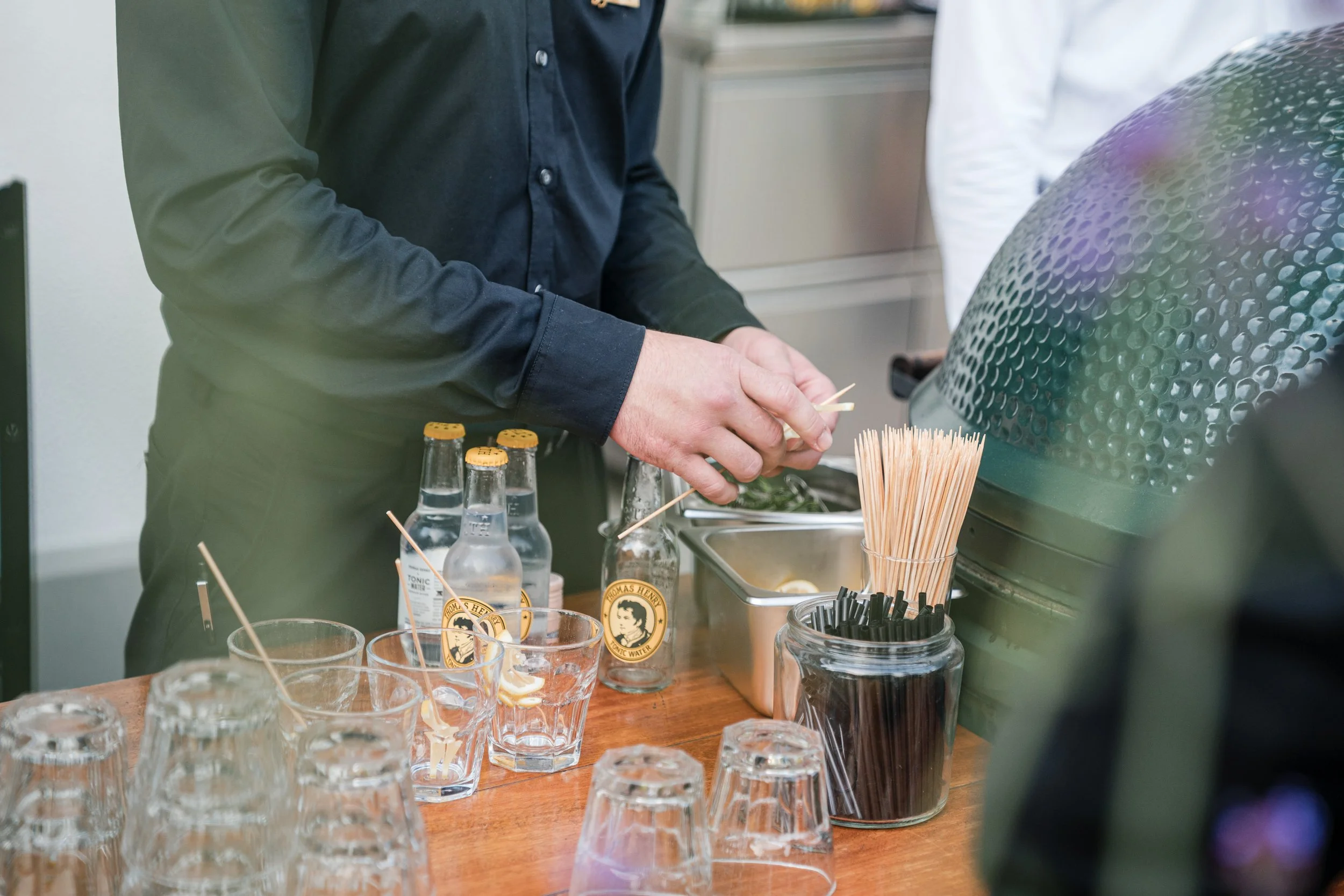 Ein Barkeeper bereitet Getränke vor, mit Gläsern, Trinkhalmen und Flaschen auf einer Bar