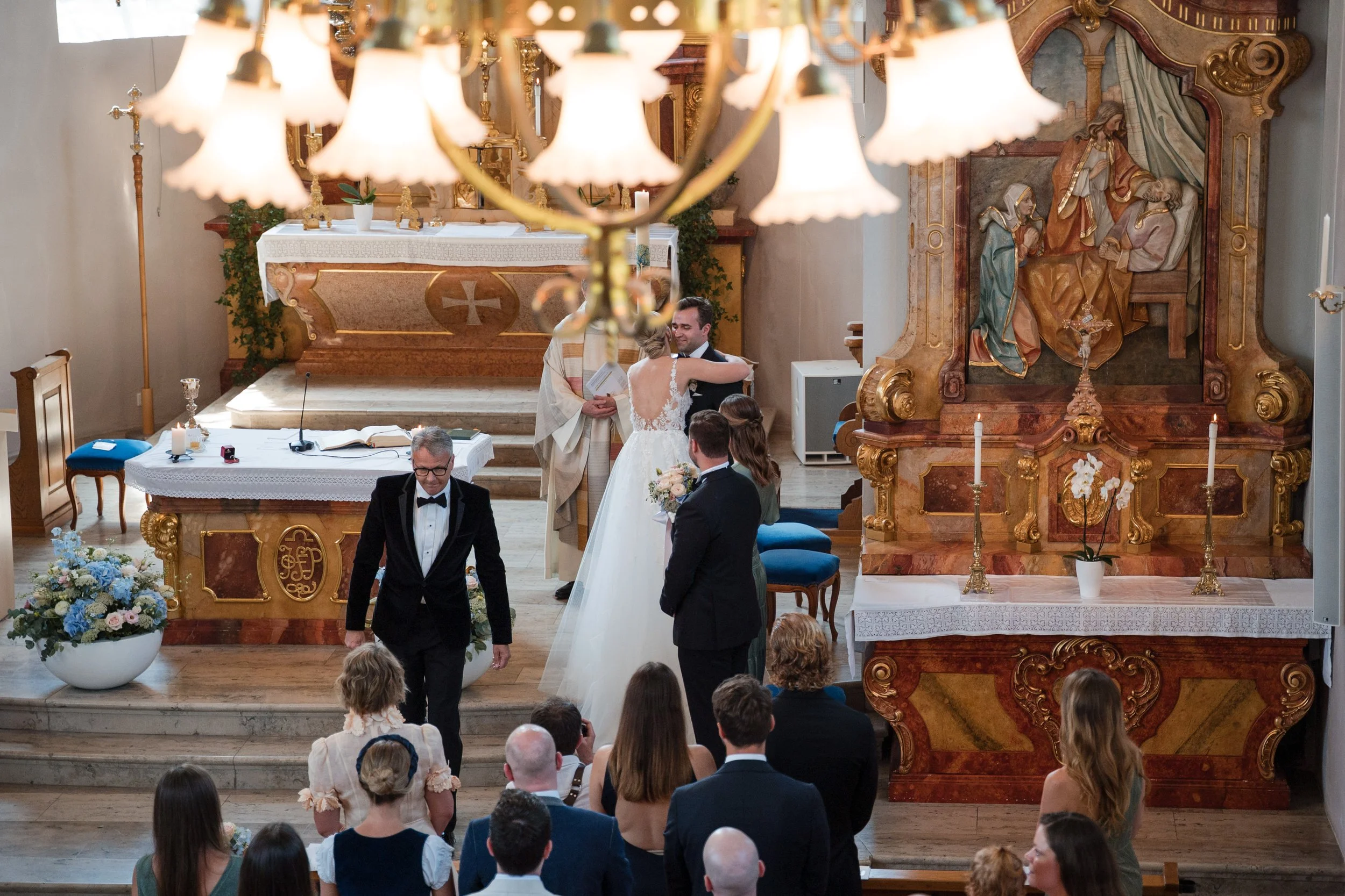 Hochzeit in einer Kirche mit Braut und Bräutigam, Pfarrer,–Gästen, Blumen und Kerzen, in einer historischen Kirche