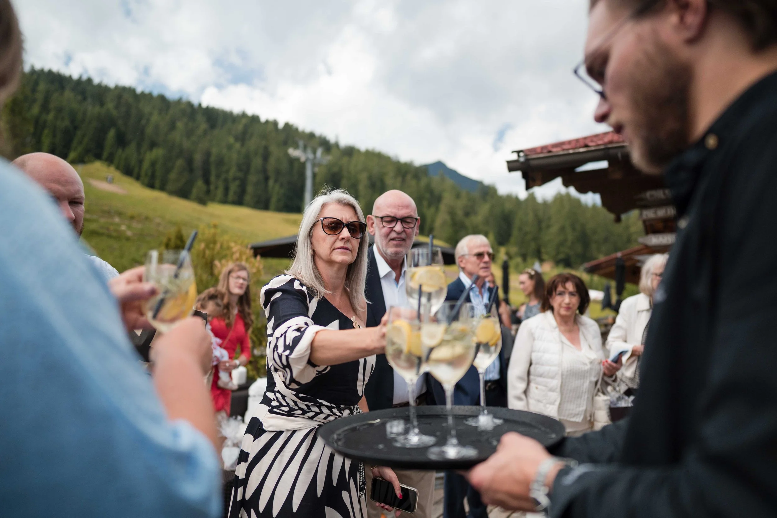 Menschen trinken Getränke mit Zitrone bei einer Outdoor-Party in einer bergigen Landschaft.