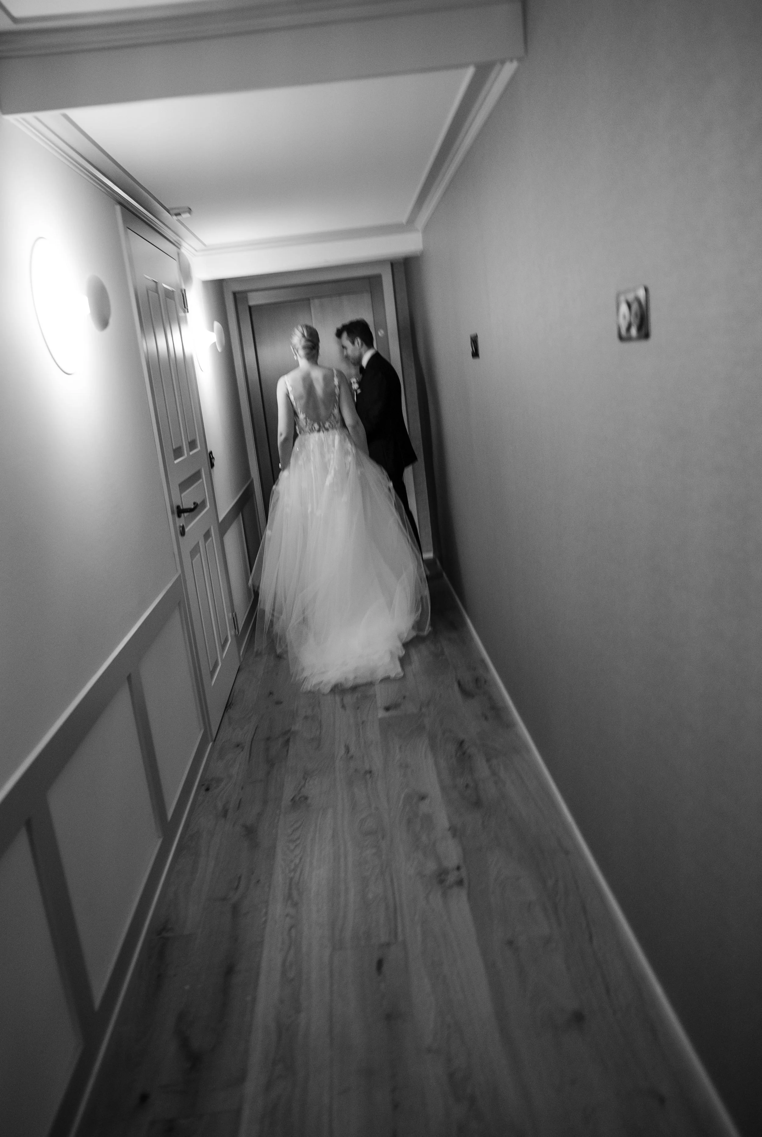 Braut und Bräutigam gehen den Flur eines Hotels, schwarz-weiß, unscharf, seitliche Ansicht.