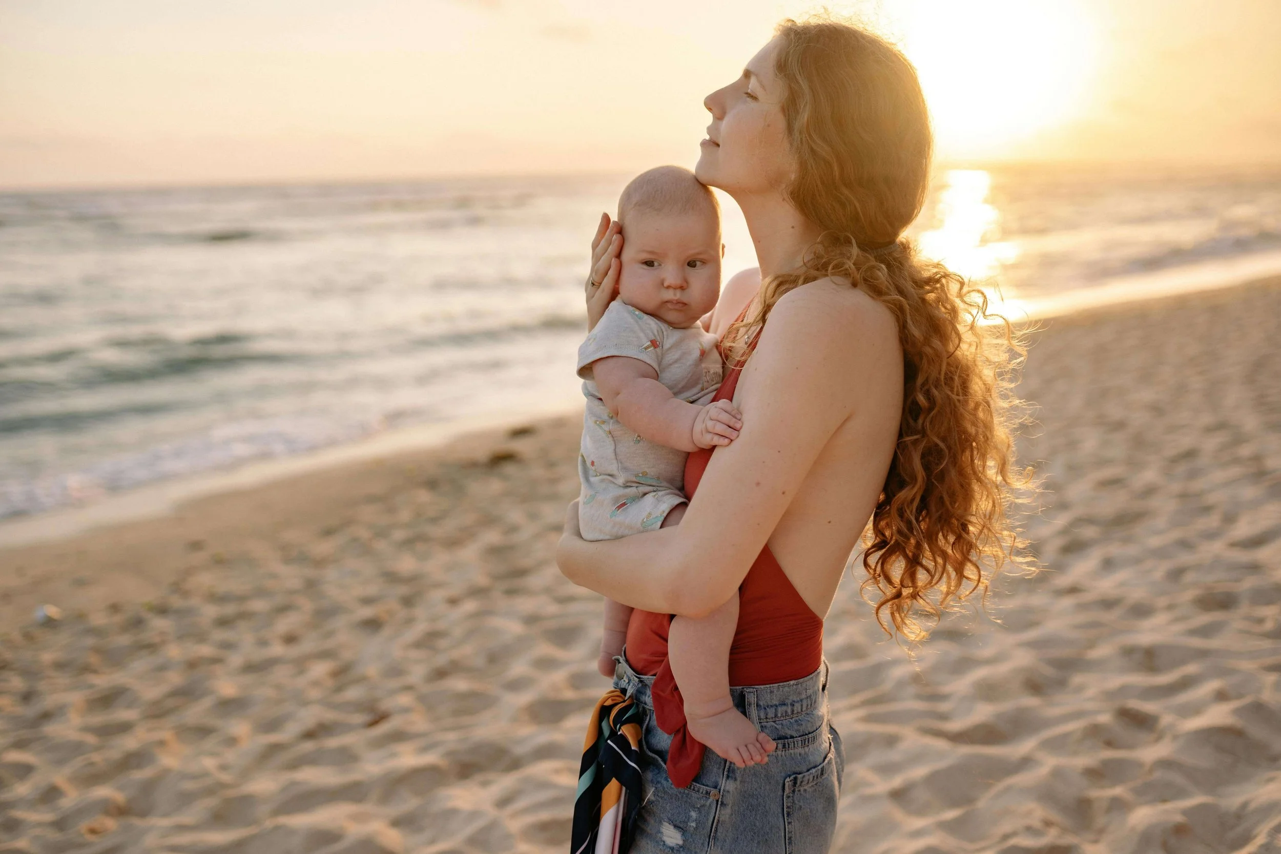 Woman smiling while holding her baby on the beach, illustrating connection and growth during the transition to motherhood in Washington, DC.