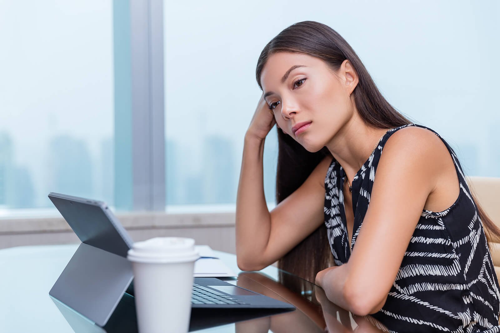 A woman stares blankly at her laptop, lost in thought, a pause someone exploring what is psychoanalysis Washington may find meaningful. Psychoanalysis Washington and Psychoanalysis in Washington, DC treat moments like this as part of the work.