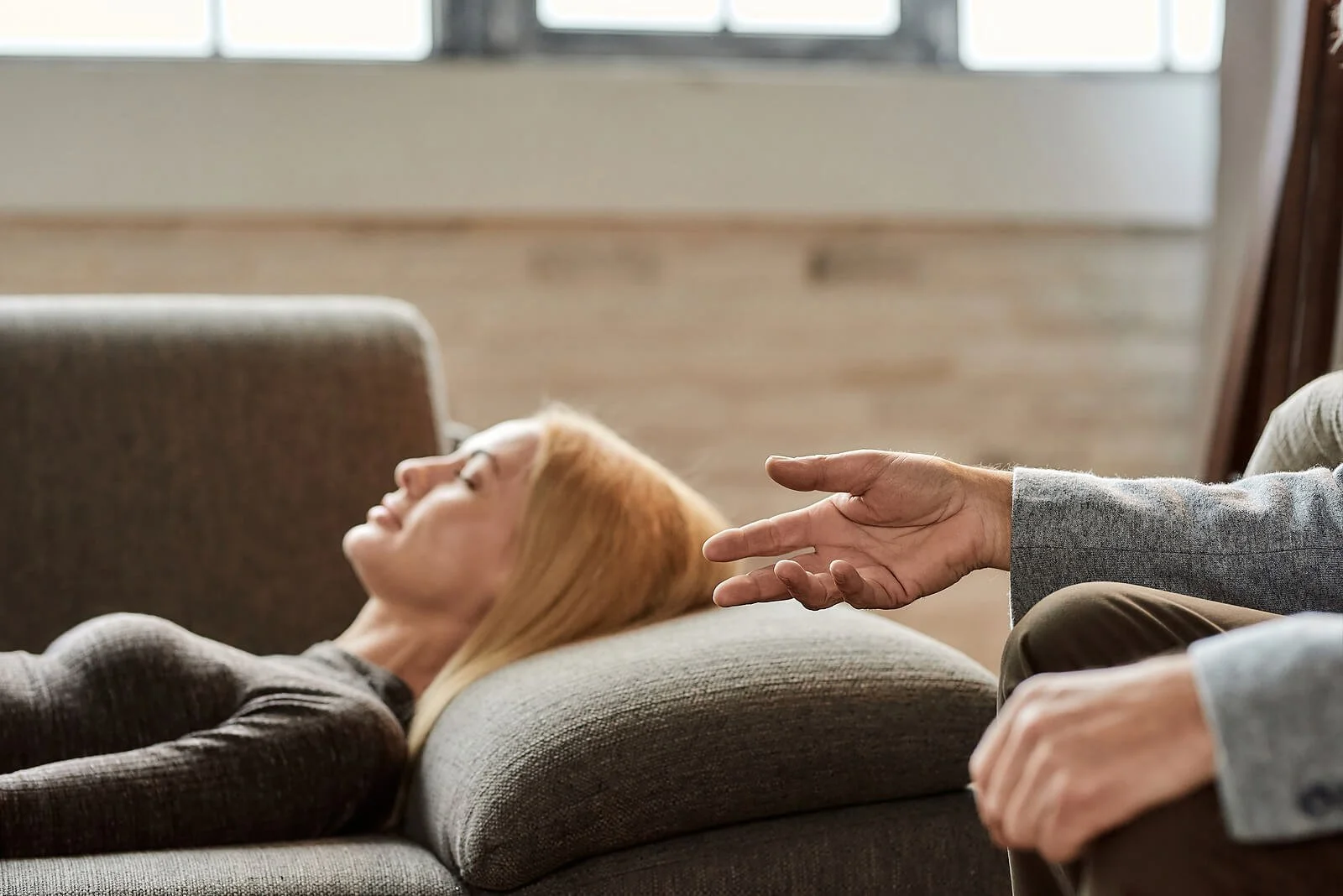 Woman lies on a therapy couch as her psychoanalyst, Washington, DC-based, reaches, illustrating what is psychoanalysis Washington clients often ask about and the psychoanalysis therapy definition Washington residents rely on.