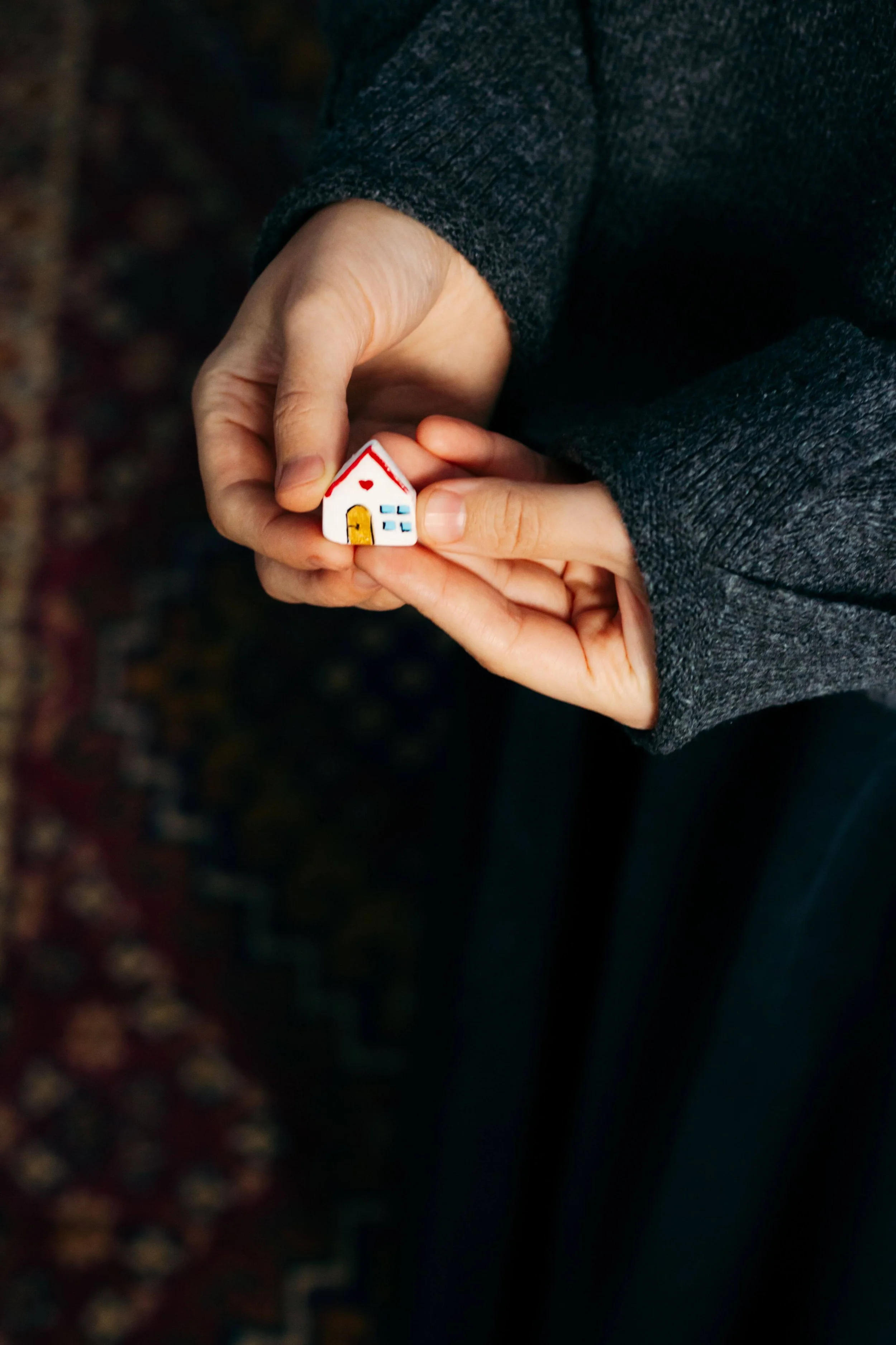 Two hands gently cradle a small toy house, symbolizing the search for belonging explored in psychodynamic therapy in Washington, DC, guided by a psychodynamic therapist in Washington, DC through a psychodynamic approach in Washington, DC.