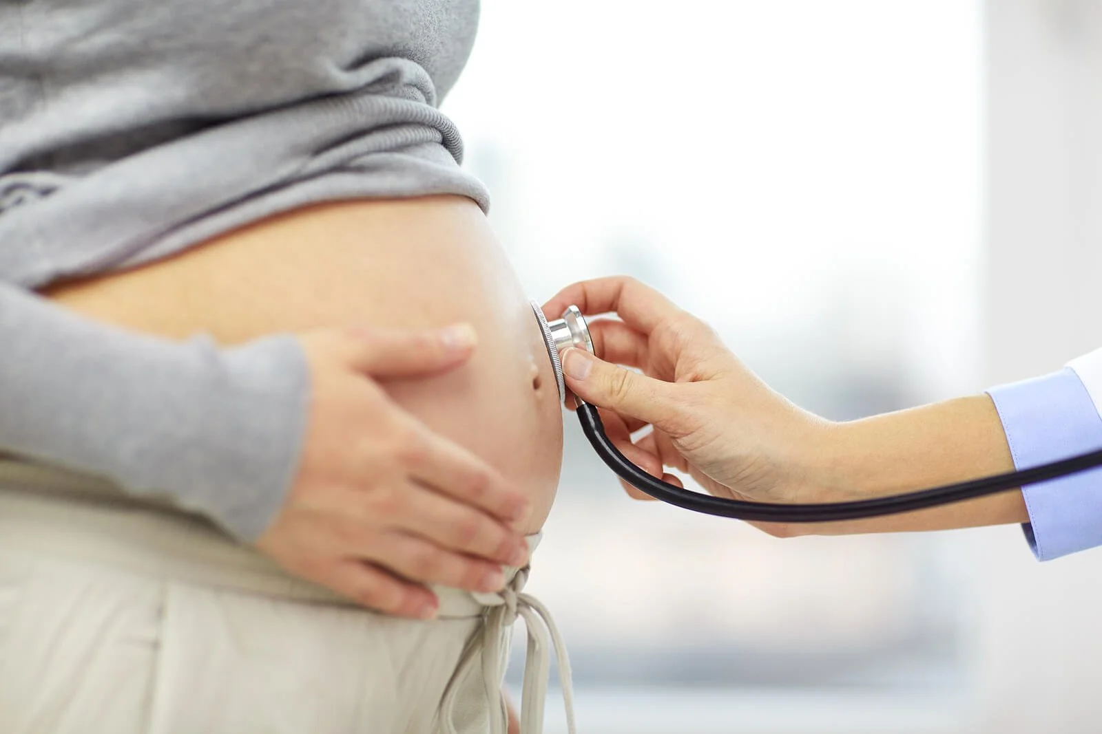 A doctor listens to a pregnant belly with a stethoscope, capturing the anticipation before birth that postpartum therapy Washington DC and postpartum therapists in DC help parents process afterward.