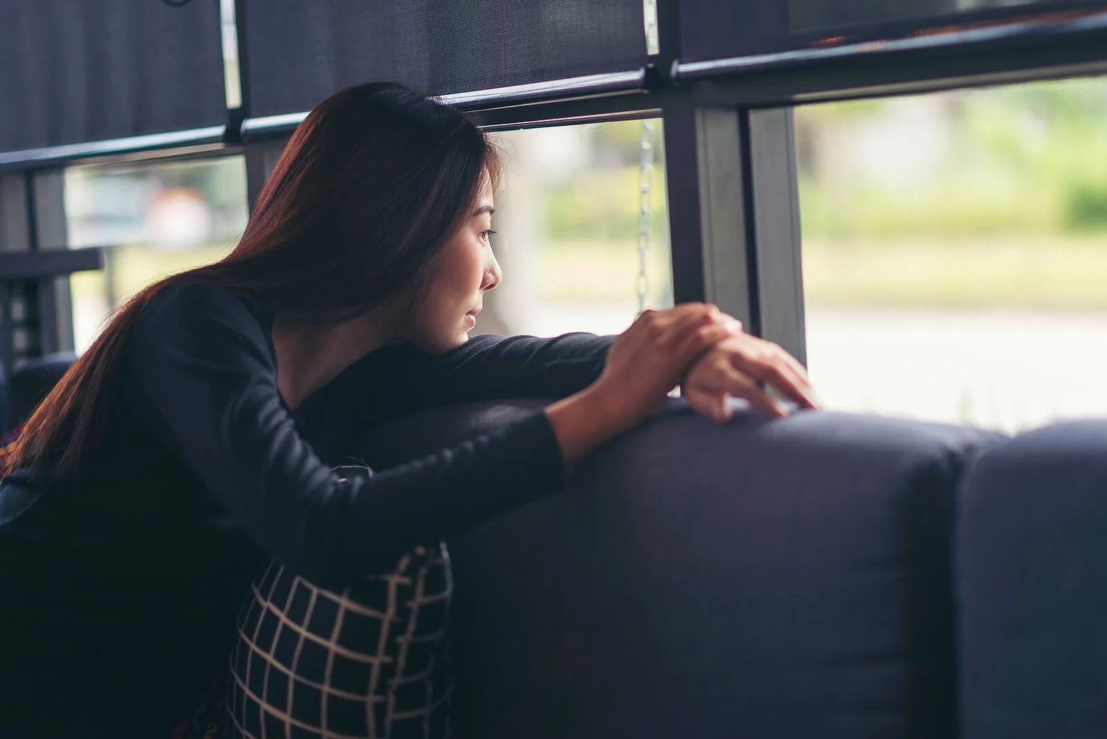 A woman gazes quietly out a window, lost in thought, reflecting the reflection at the heart of psychodynamic therapy in Washington, DC and psychodynamic psychotherapy Washington, DC with a psychodynamic therapist in Washington, DC.