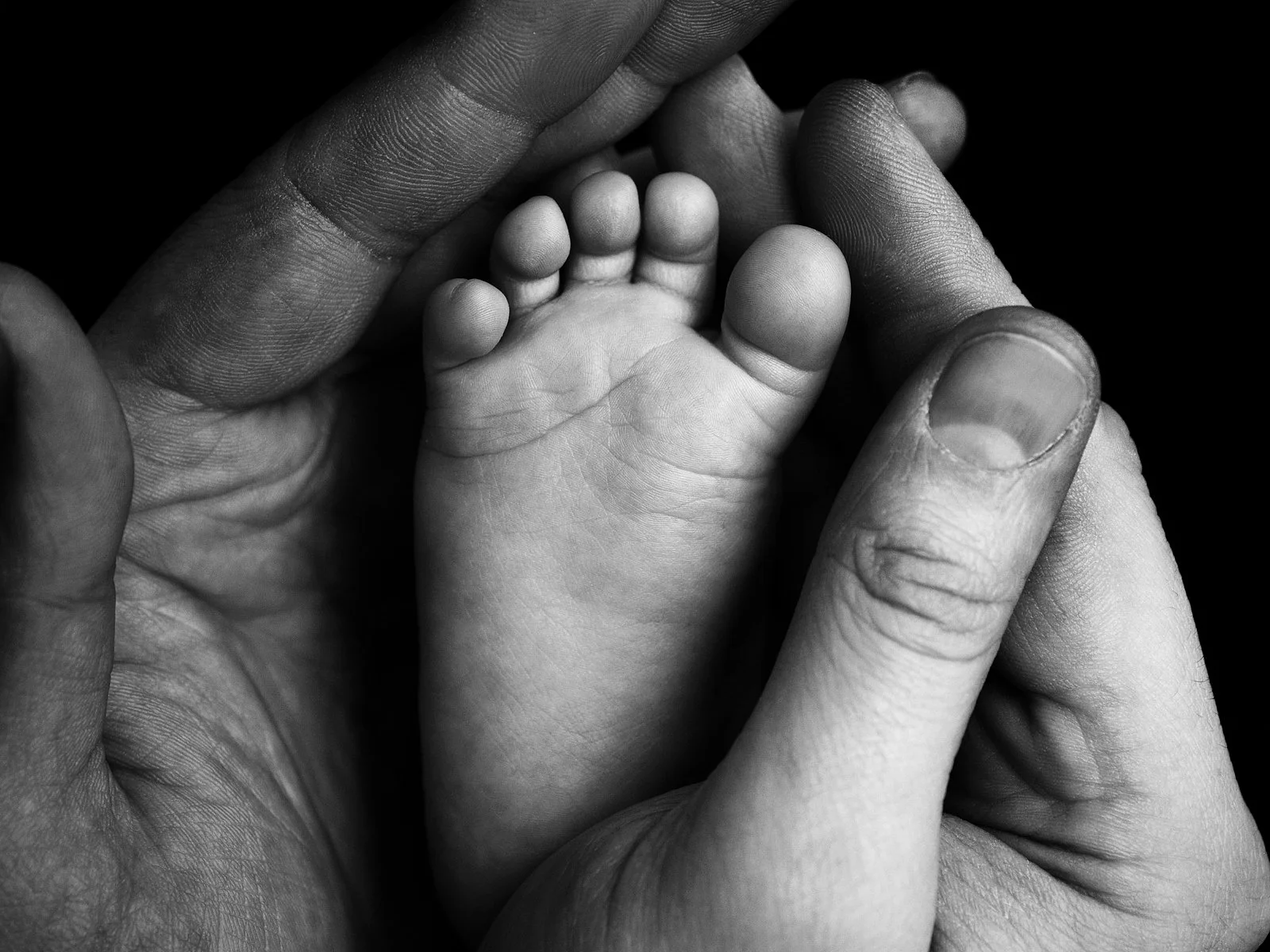 A parent gently cradles a newborn foot in their hands, a tender moment reflecting postpartum mental health Washington DC and maternal mental health support Washington DC, part of postpartum depression treatment Washington DC.