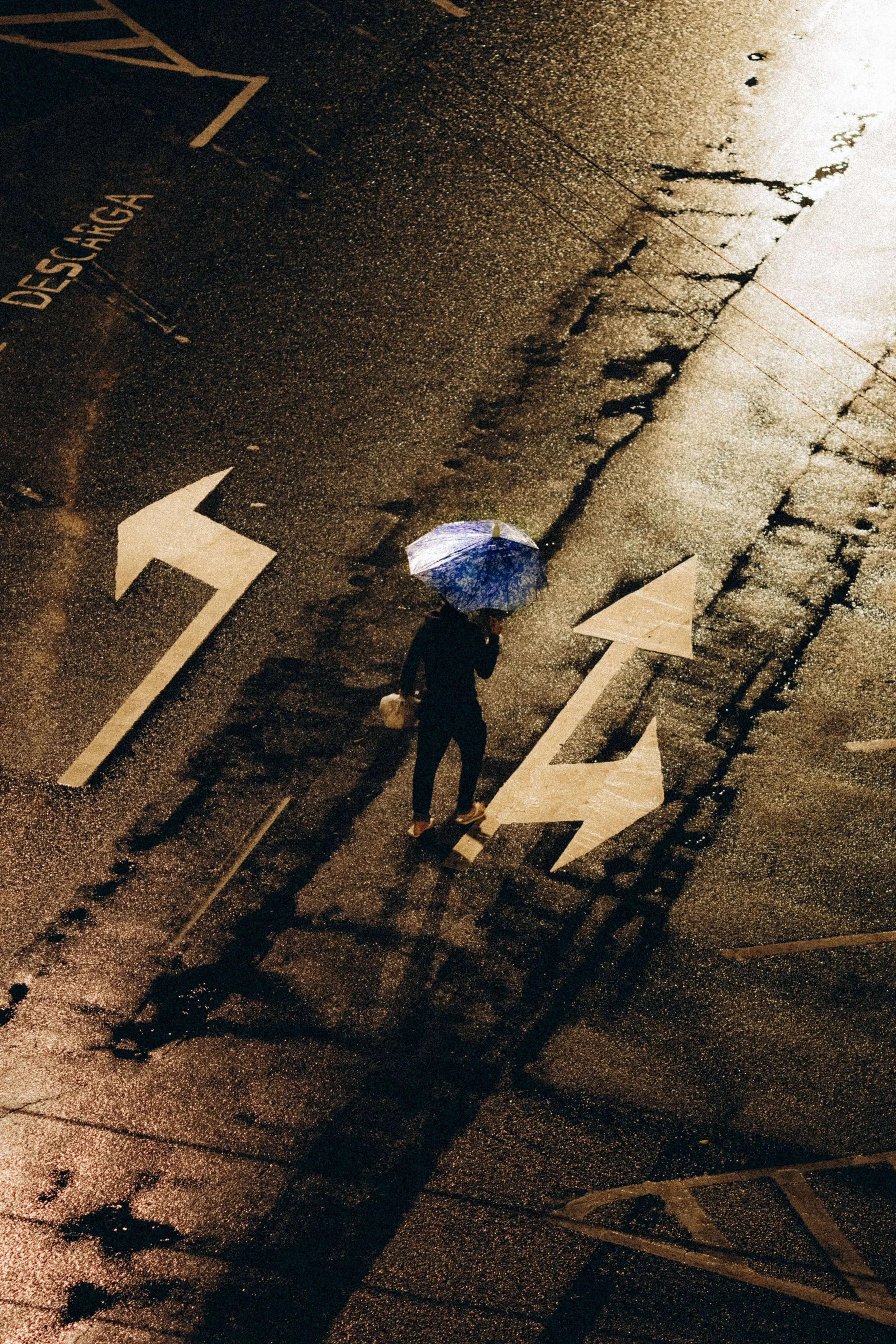 A person with an umbrella stands at a crossroads of painted arrows, representing the pull between identities explored in psychodynamic therapy in Washington, DC, with a psychodynamic therapist in Washington, DC.