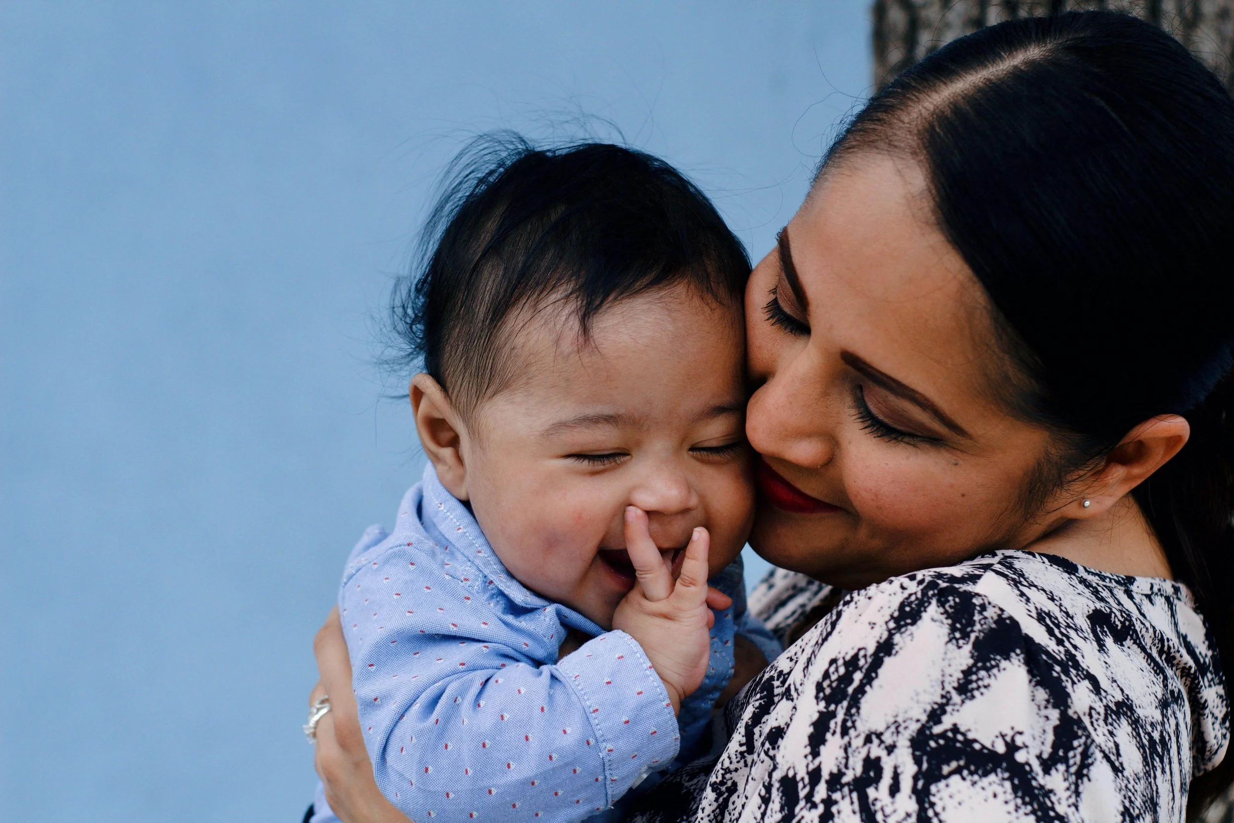 Woman holding her baby close and smiling, illustrating connection supported by postpartum therapy for cultural expectations in Washington, DC.