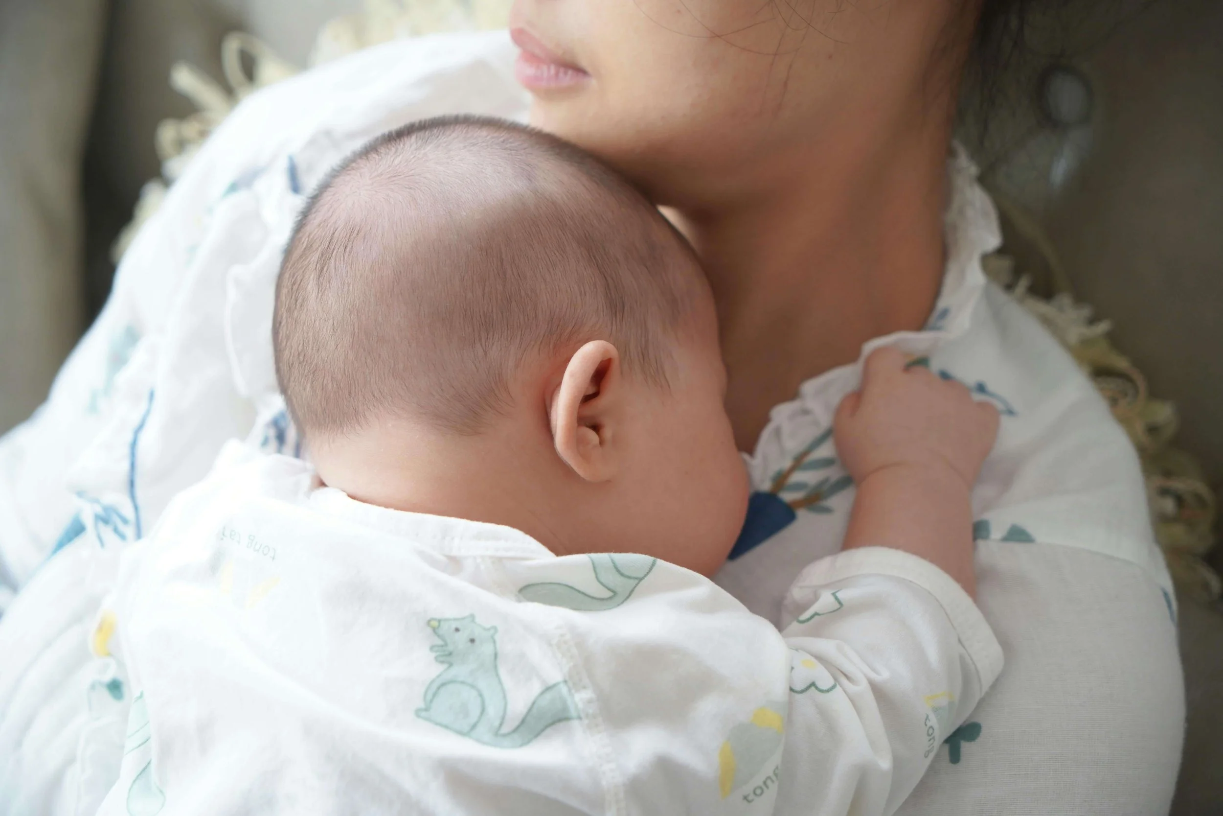 New parent holding a newborn close to their chest, reflecting the quiet emotional weight and postpartum expectations in Washington, DC.