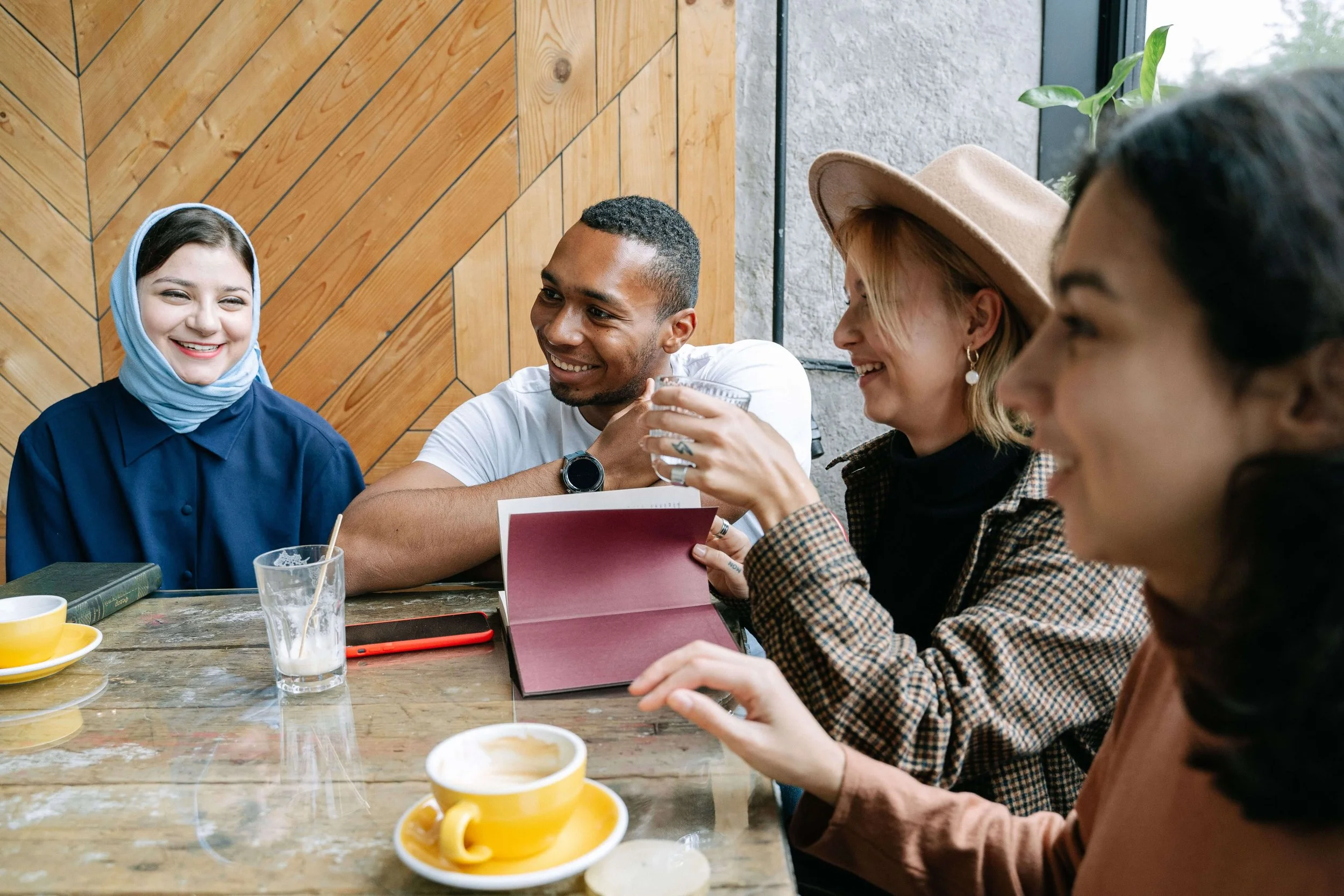A diverse group of friends laughs together over coffee, reflecting the connection often discussed in psychodynamic therapy Washington DC with a psychodynamic therapist Washington, DC offering psychodynamic psychotherapy Washington, DC.