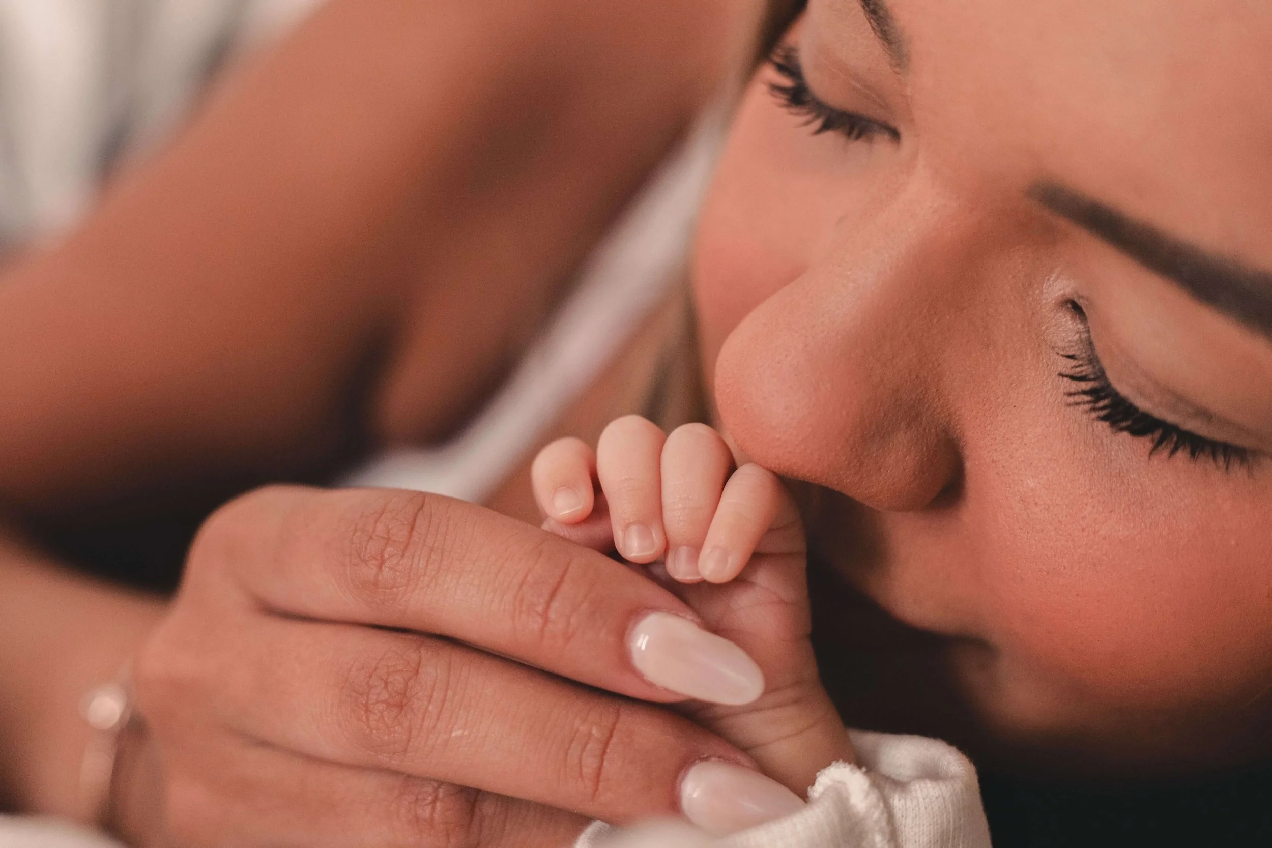 A mother tenderly kisses her newborn hand, a quiet bonding moment that psychodynamic postpartum therapy Washington DC helps process alongside postpartum depression Washington DC and support from postpartum therapists in DC.