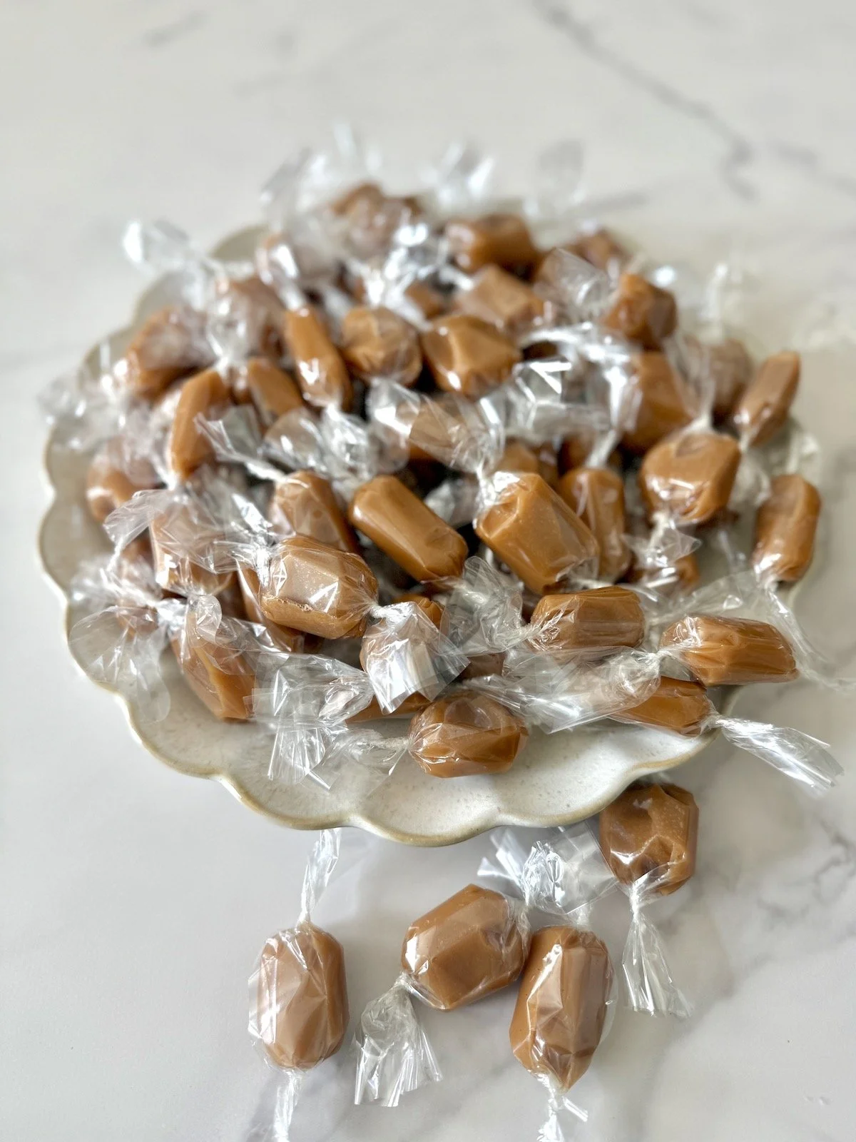 Individually wrapped caramels on scalloped beige plate