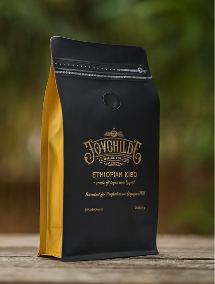 Black and yellow coffee bag with JOVGHILD logo and Ethiopian Kibo label on a wooden surface.