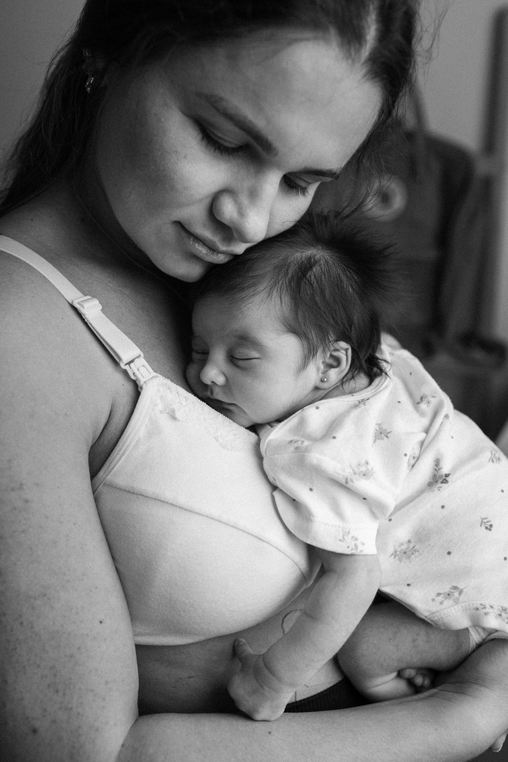 A mother cradling her sleeping infant in a black and white photo, symbolizing the quiet moments of early motherhood and postpartum care with Laura Todd, LPCC.