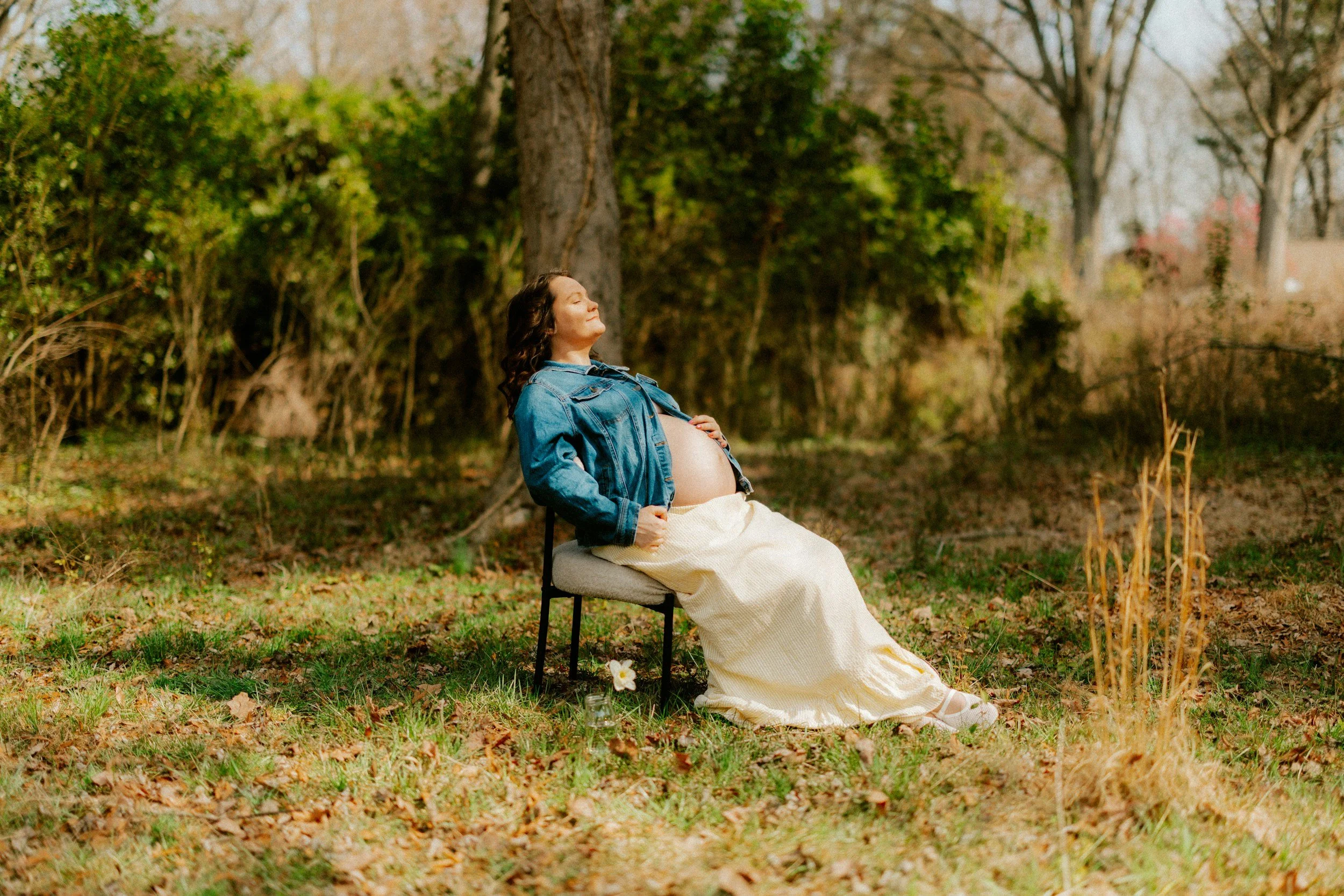 Pregnant mother sitting in a chair in the sun, practicing somatic grounding.