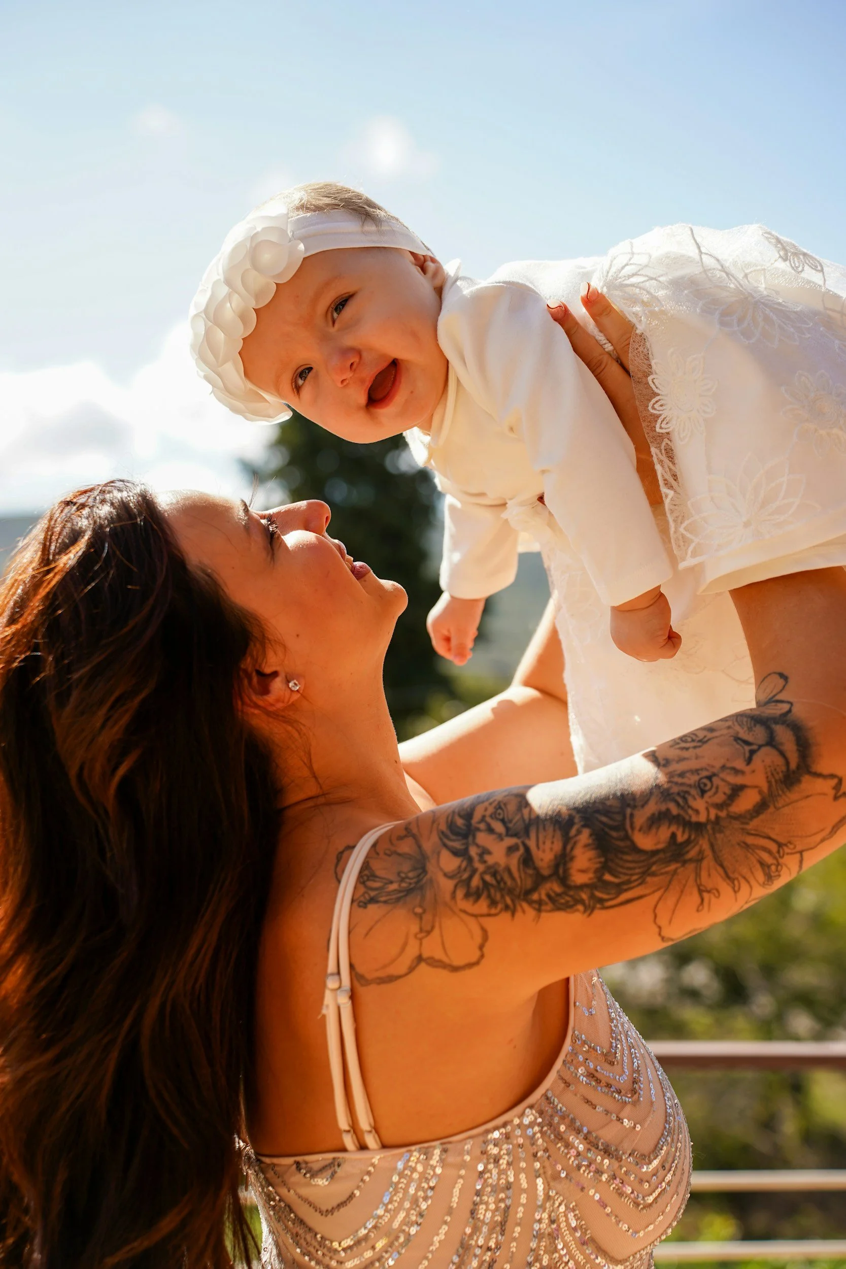 A mother joyfully lifting her baby into the air after processing birth trauma and finding present connection at Early Bonds Therapy.