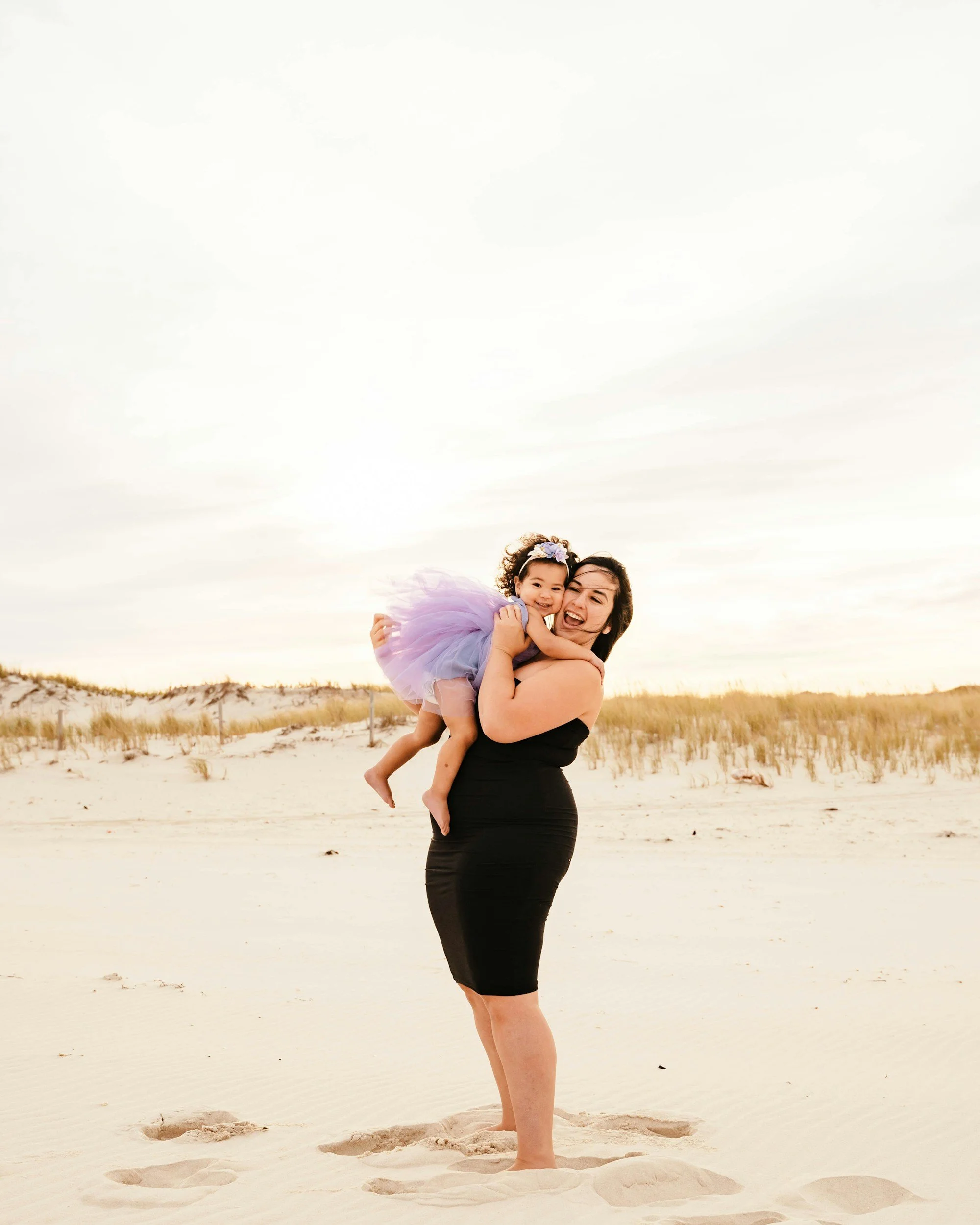 A mother holding and hugging her infant close on a California beach, reflecting emotional regulation and restored attachment after EMDR trauma recovery.