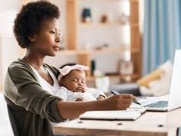Mother holding a sleeping newborn while writing, navigating the identity earthquake.