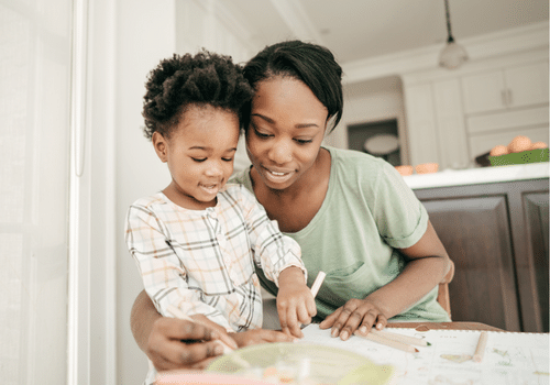 A calm and happy mother staying engaged and present with her baby while they color together