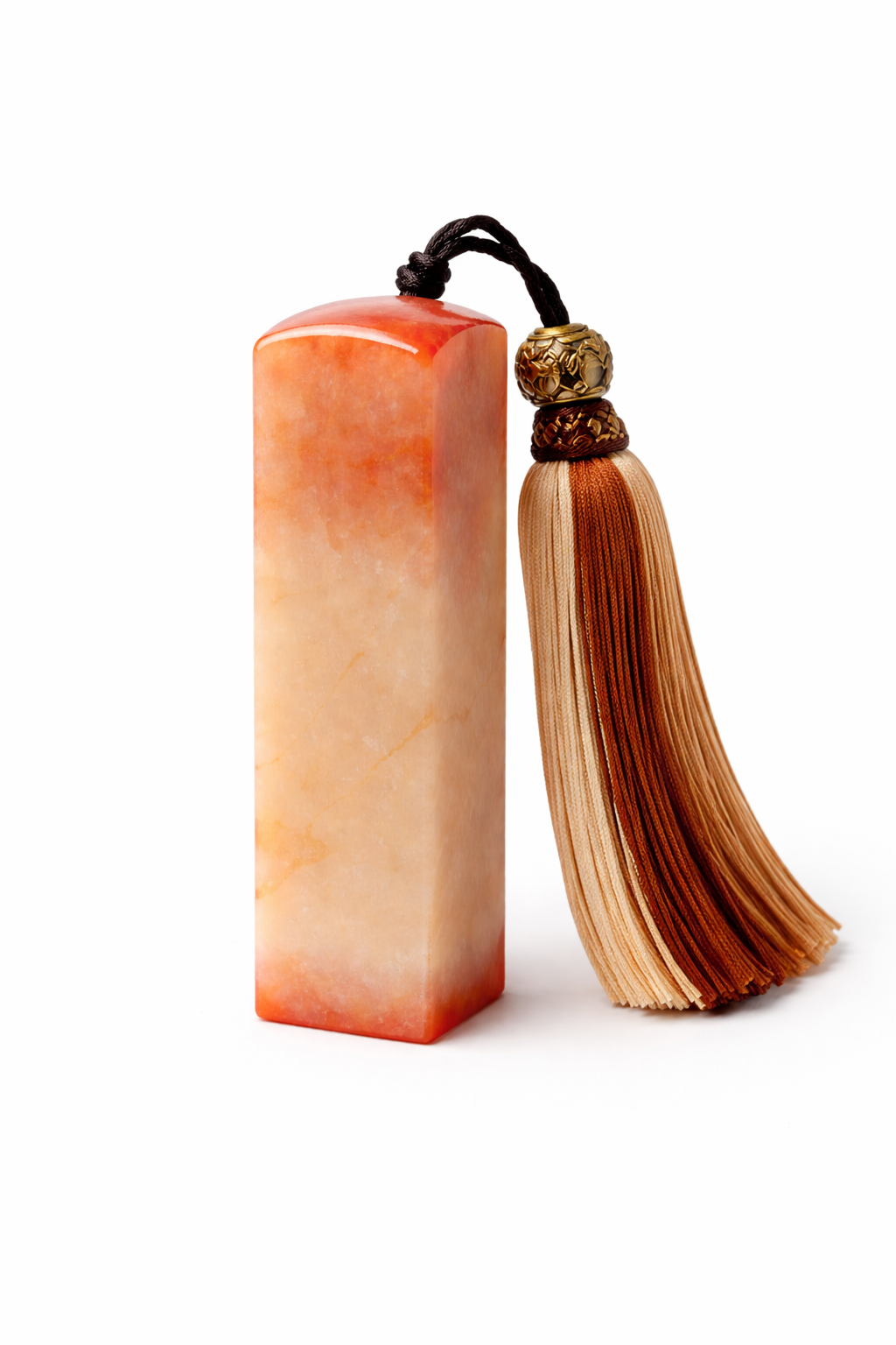 A rectangular orange and cream-colored stone with a tassel and decorative beads attached to a black cord.