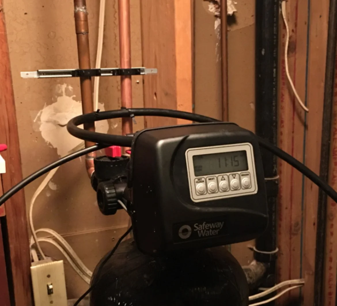 Water softener system with digital control panel in a basement utility area.