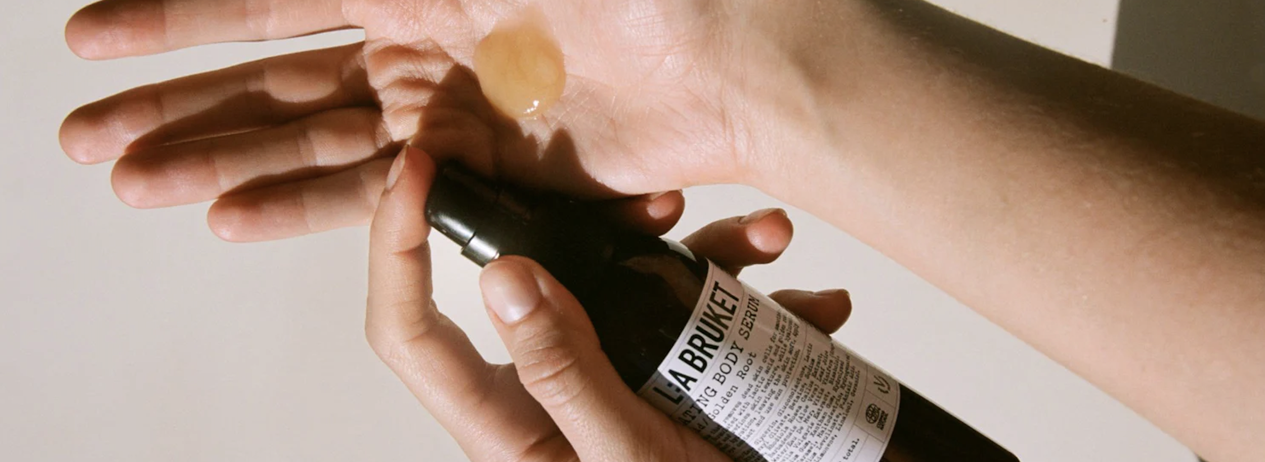 L:A Bruket body serum applied to skin in a close tactile skincare composition.