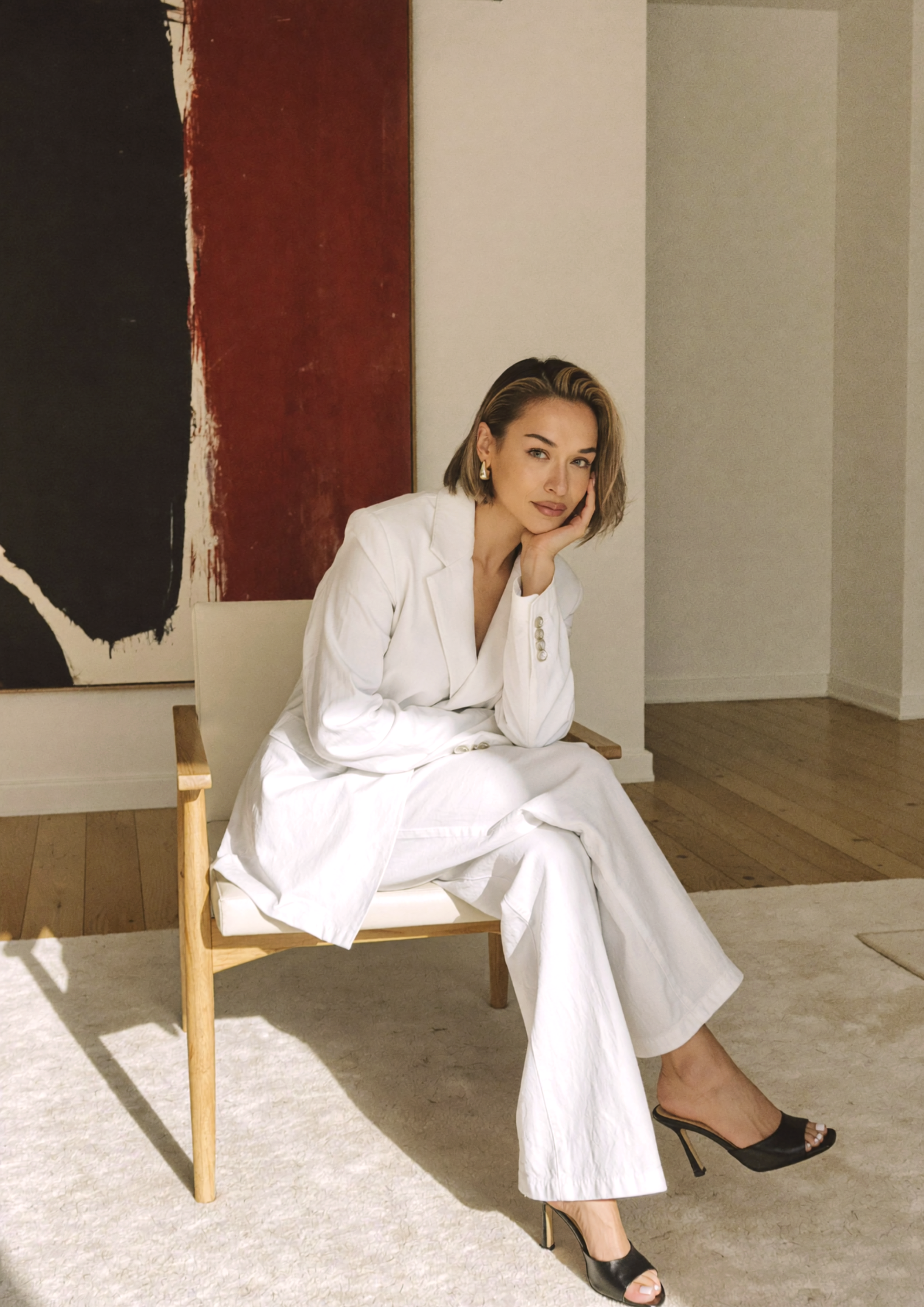 Mira Zagorova seated in a white suit in a minimalist interior, photographed for Maison Gia.