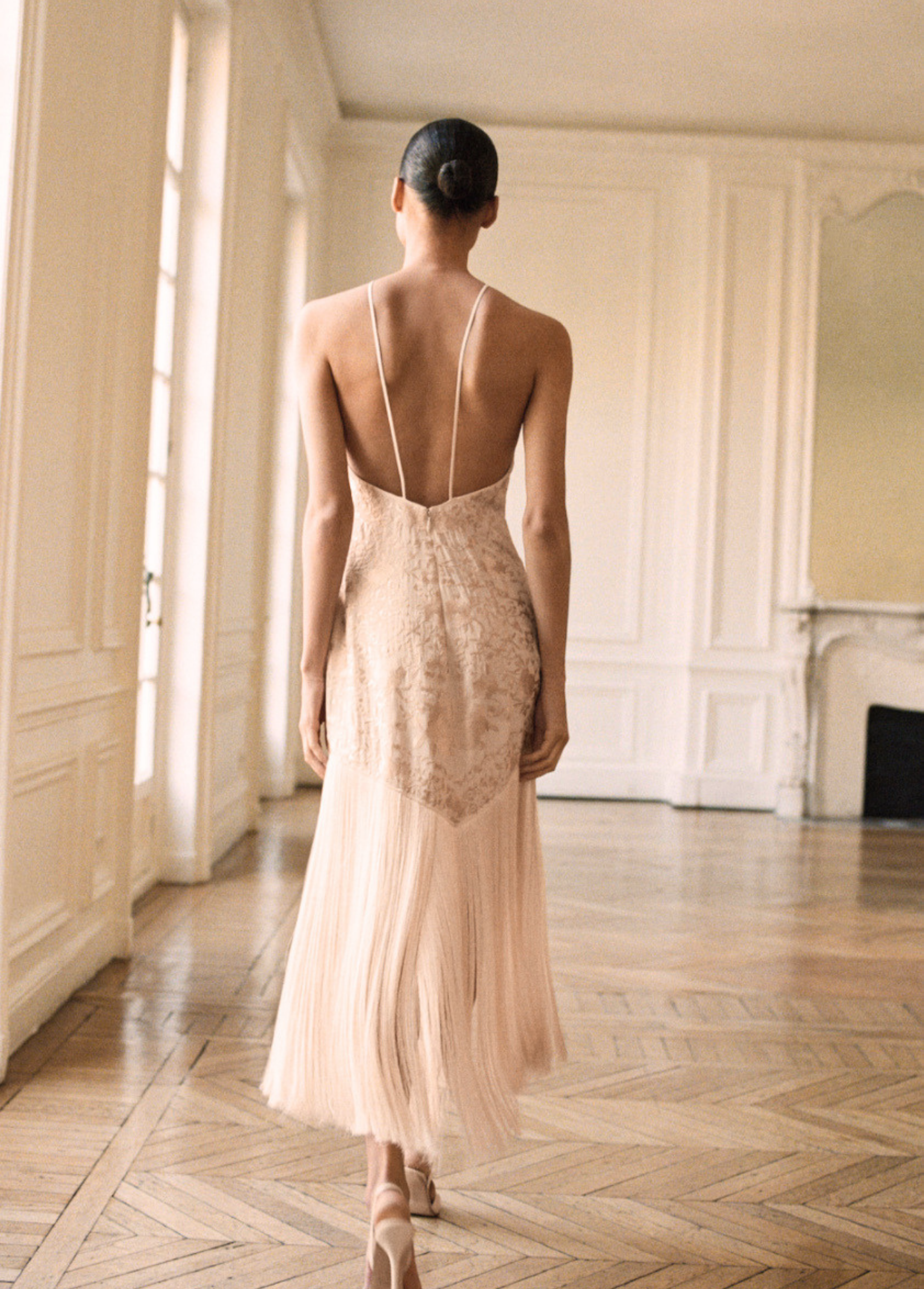 Mango fashion editorial featuring a nude backless evening gown in a softly lit Parisian interior.