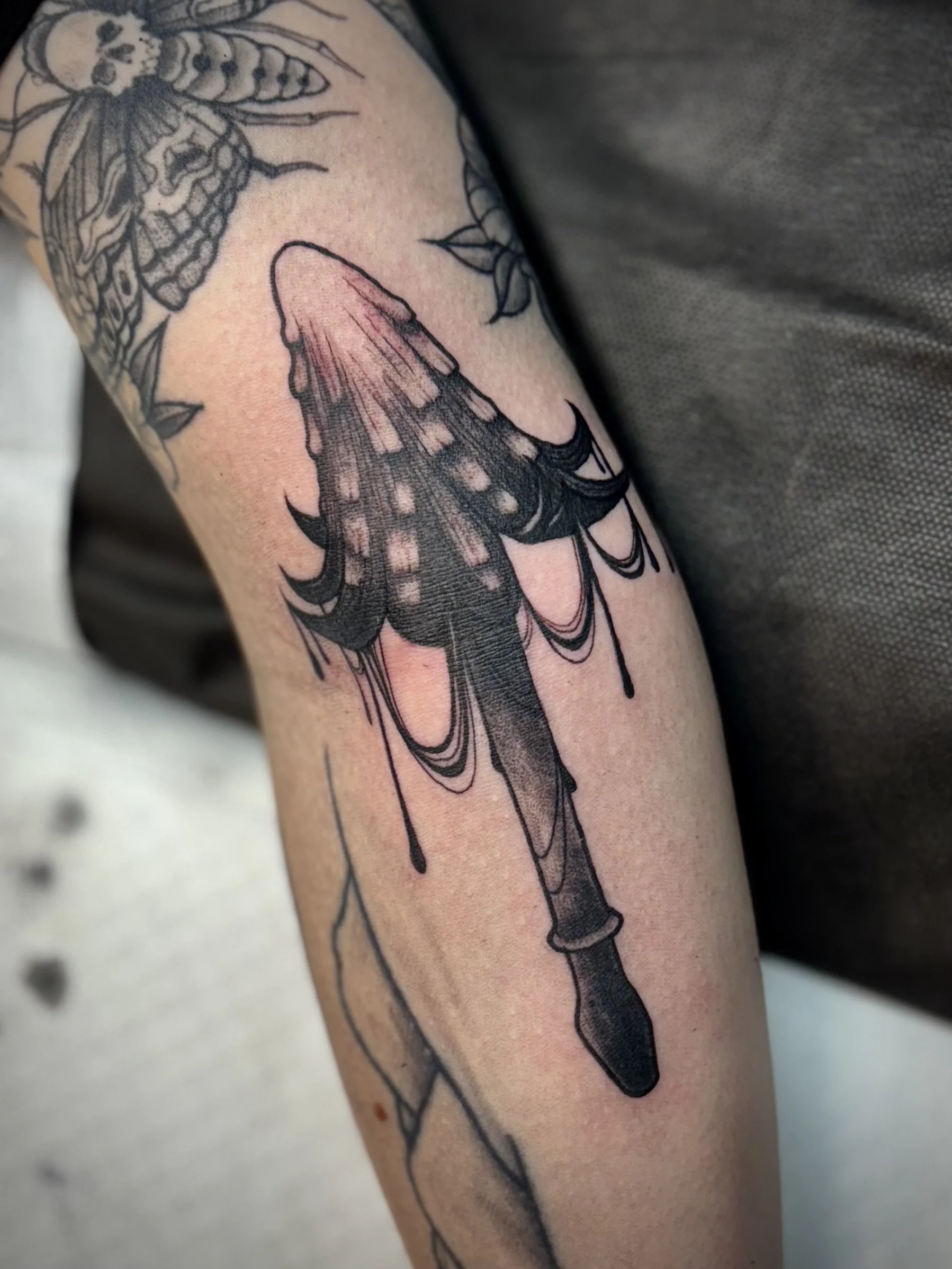 A black and grey tattoo of a stylized inky cap mushroom.