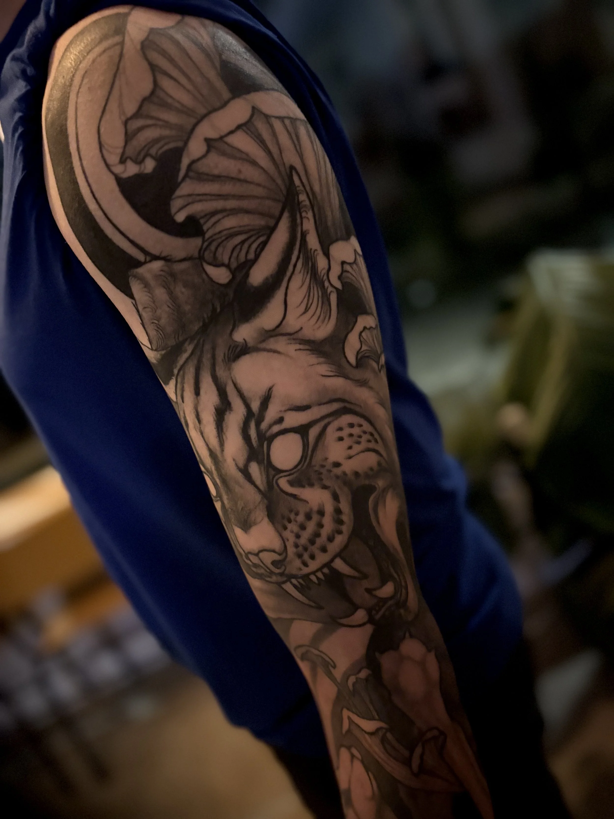 Close-up of a detailed black and grey tattoo sleeve of a snarling bob cat face on a person's upper arm.