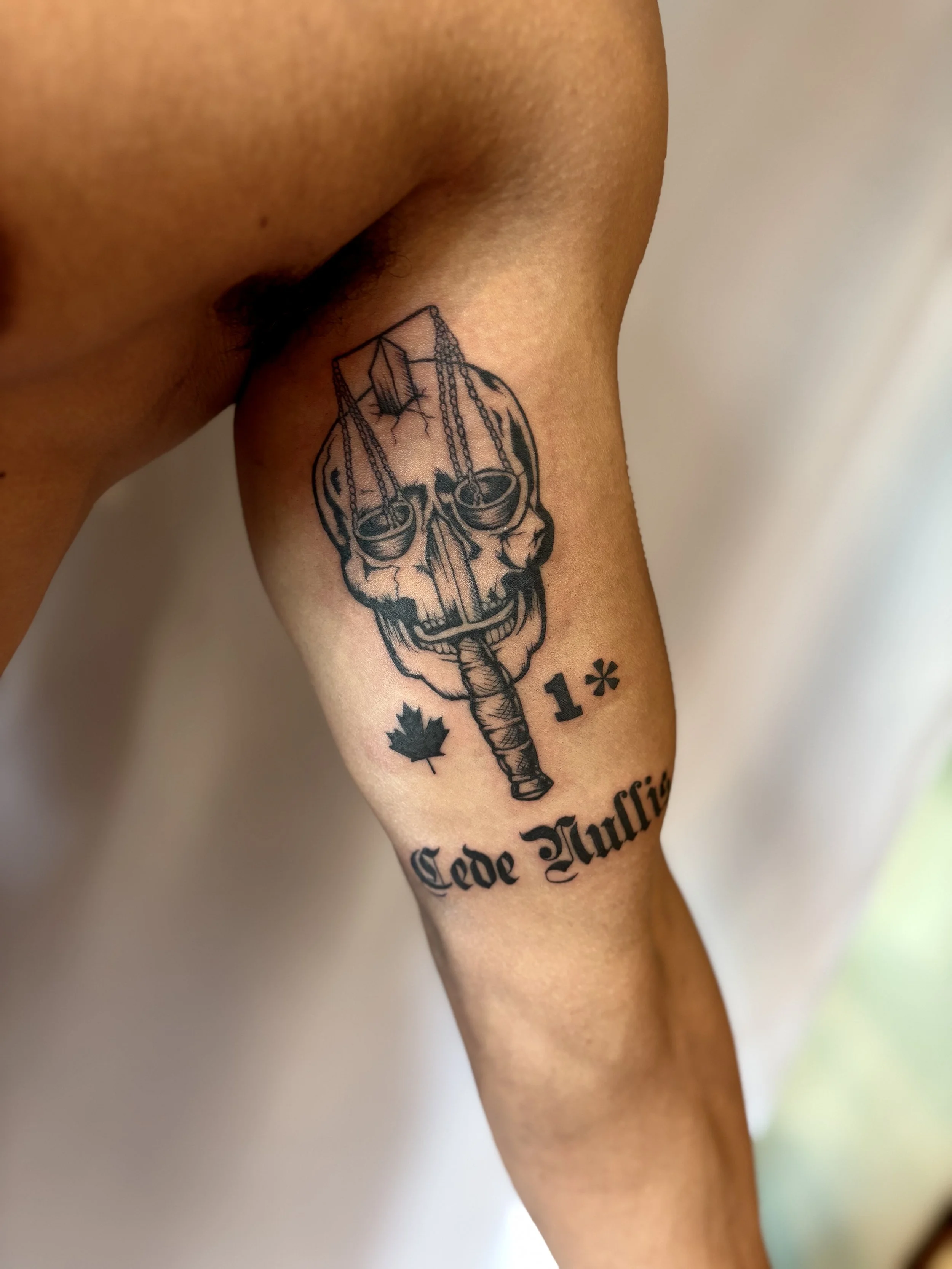 Tattoo of a skull with scales hanging from it, a knife through it, a maple leaf, a star, and 'Code Muffle' written below.