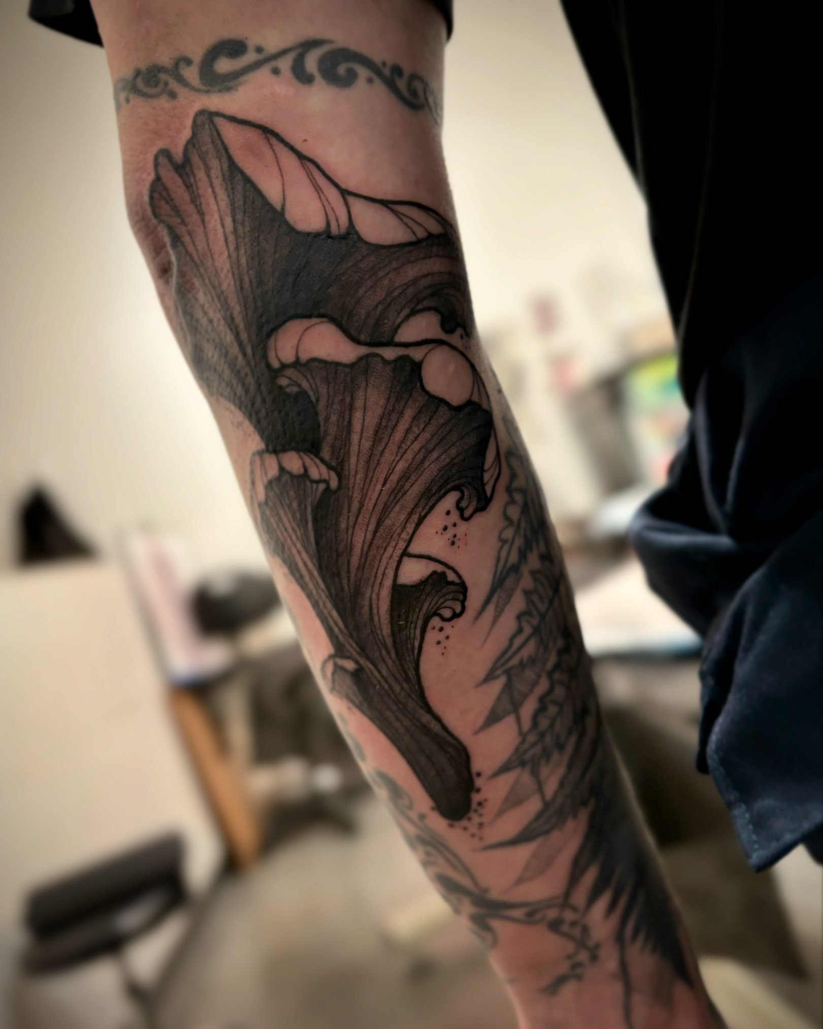 Black and gray tattoo of a stylized chanterelle mushroom on a person's forearm.