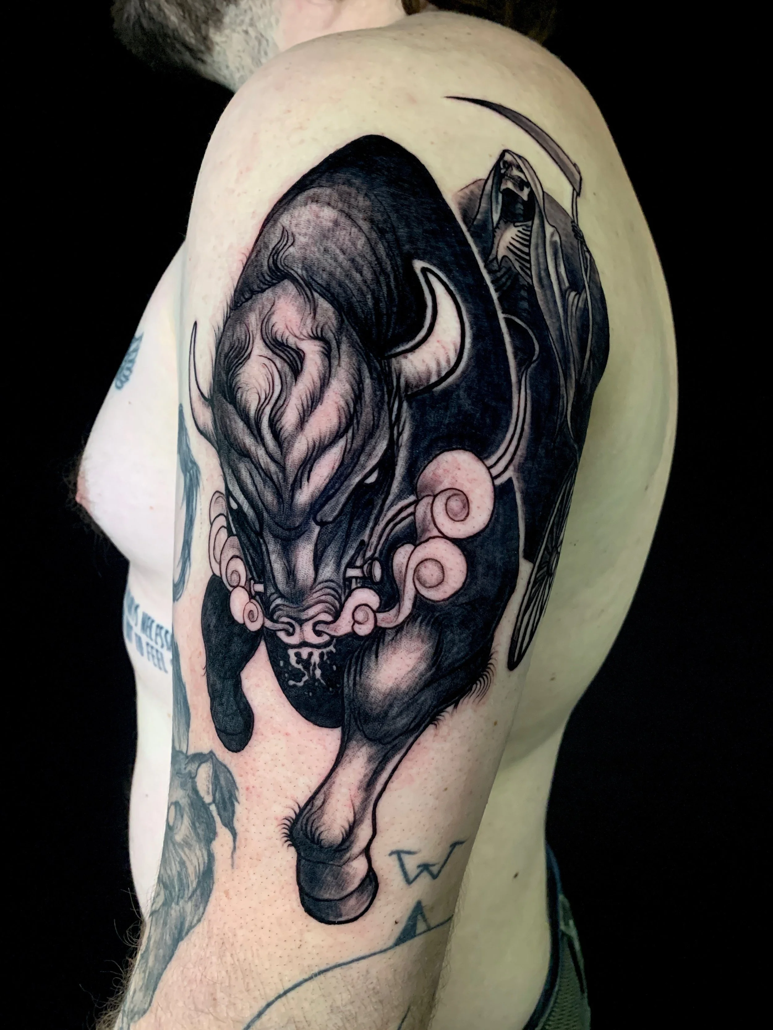 Tattoo of a fierce feline creature with flowing mane, horns, and smoke details on a person's upper arm.