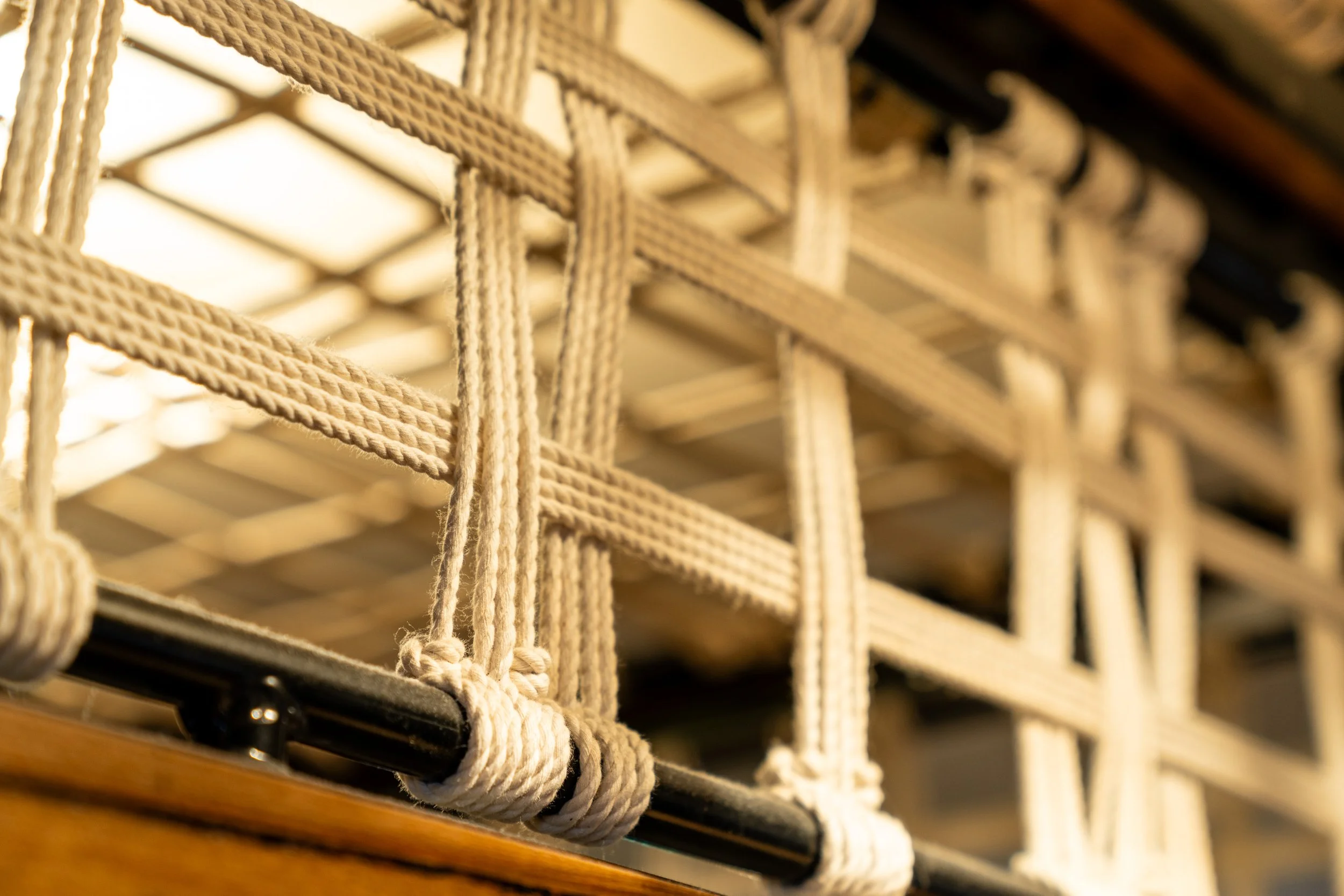 Close-up of a rope netting with knots attached to a bar.