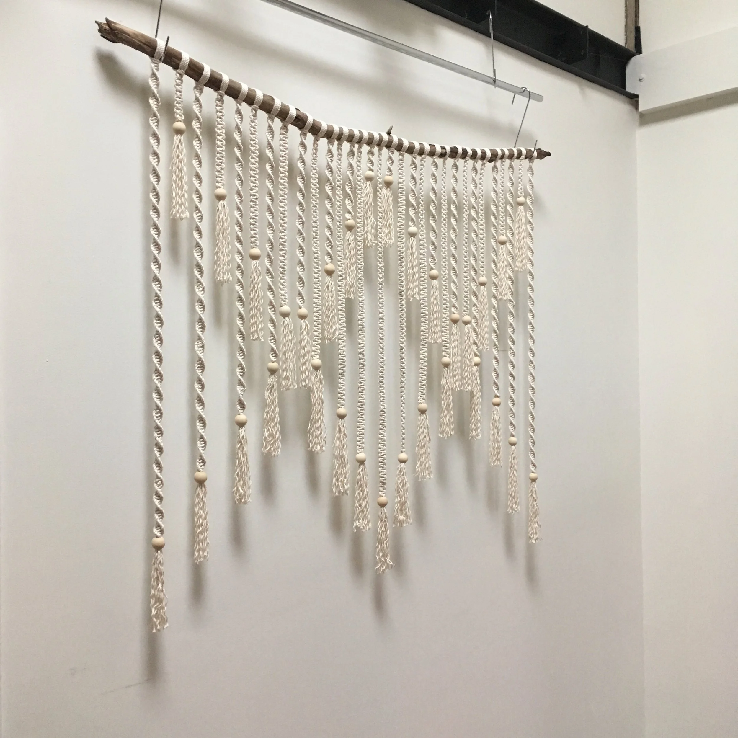 Macrame wall hanging with wooden beads on a wooden rod