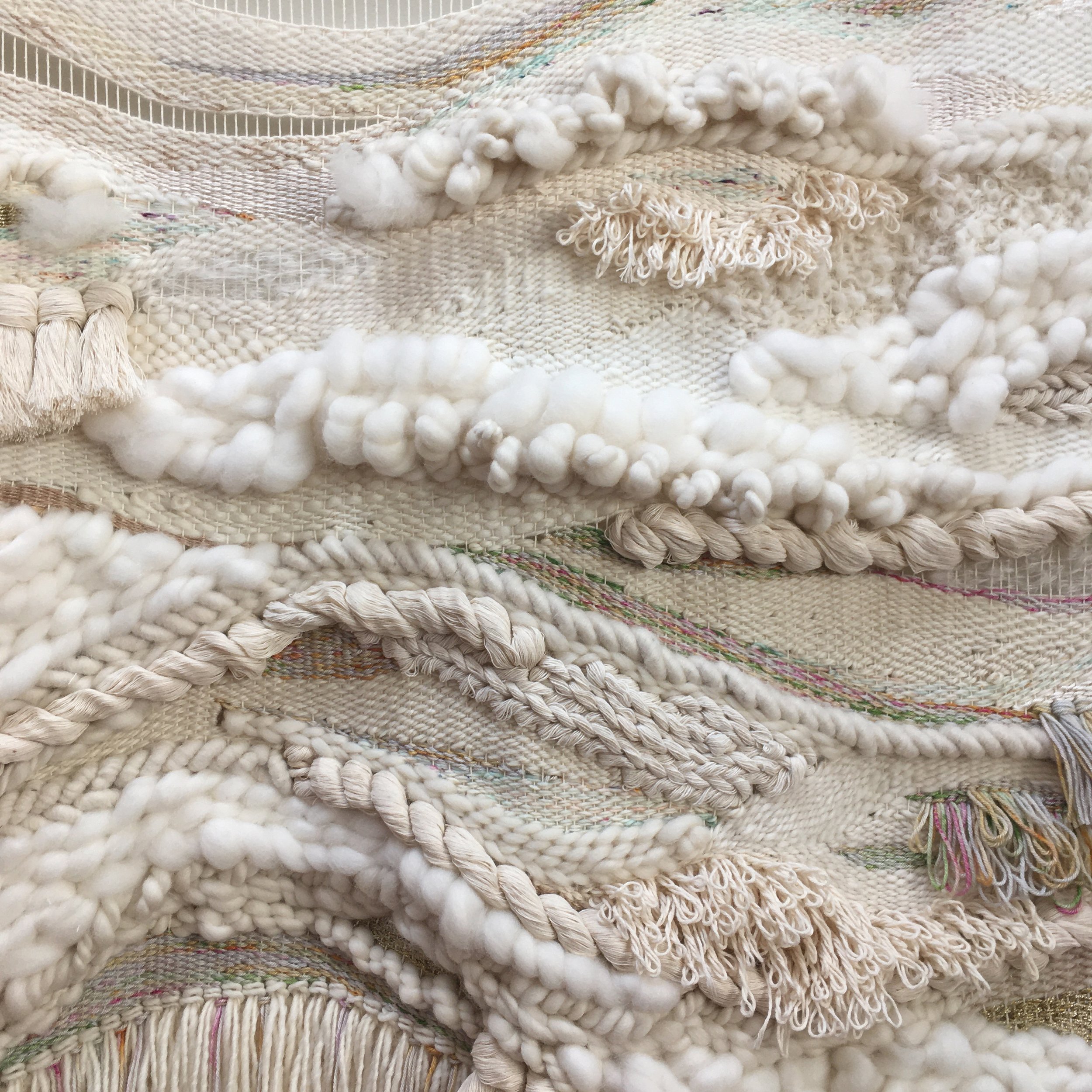 Intricate woven textile with various textures and patterns, featuring thick, twisted yarns and subtle color variations in cream and beige tones.
