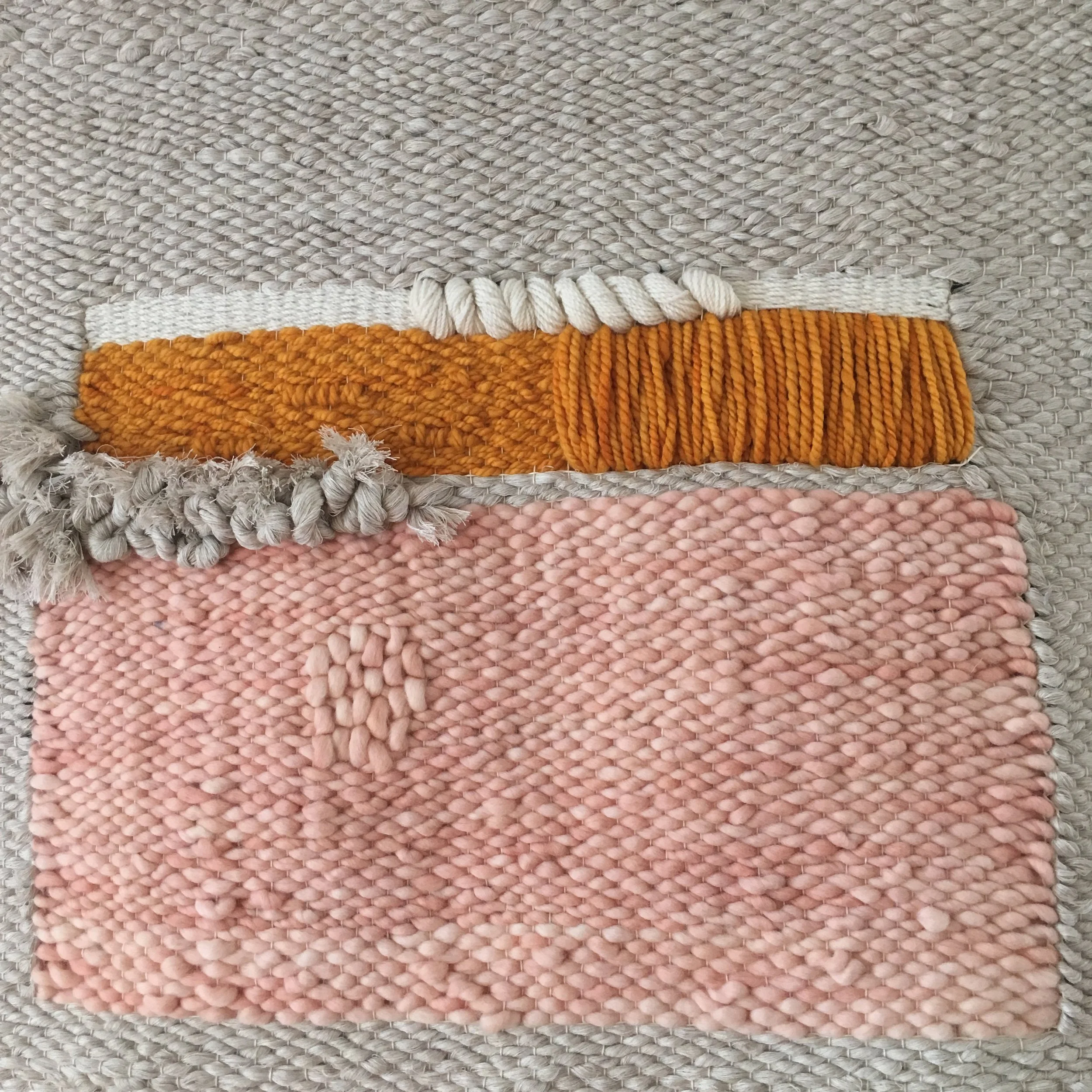 Textured woven tapestry with pink, orange, and beige sections.
