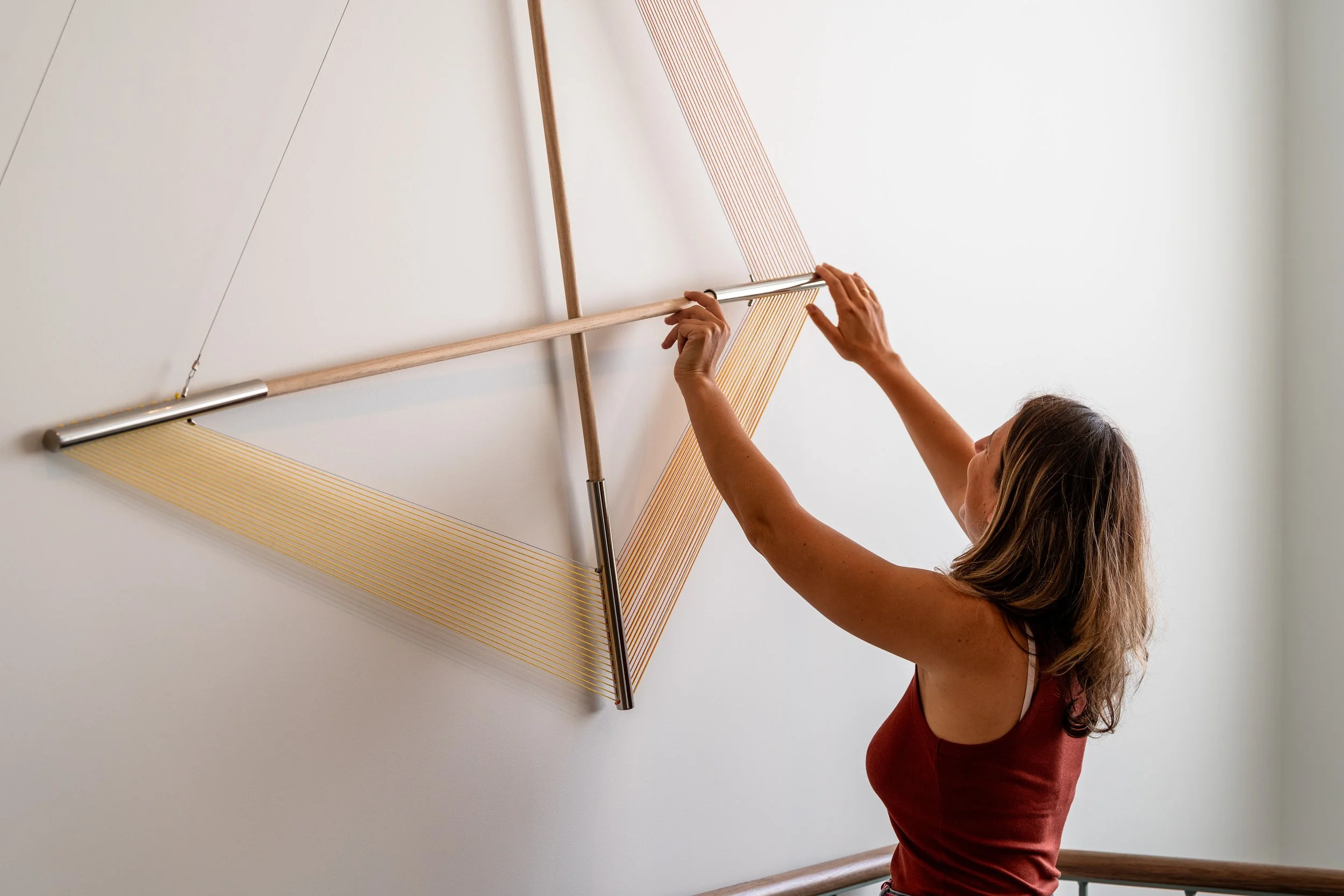 Woman adjusting modern art installation on wall